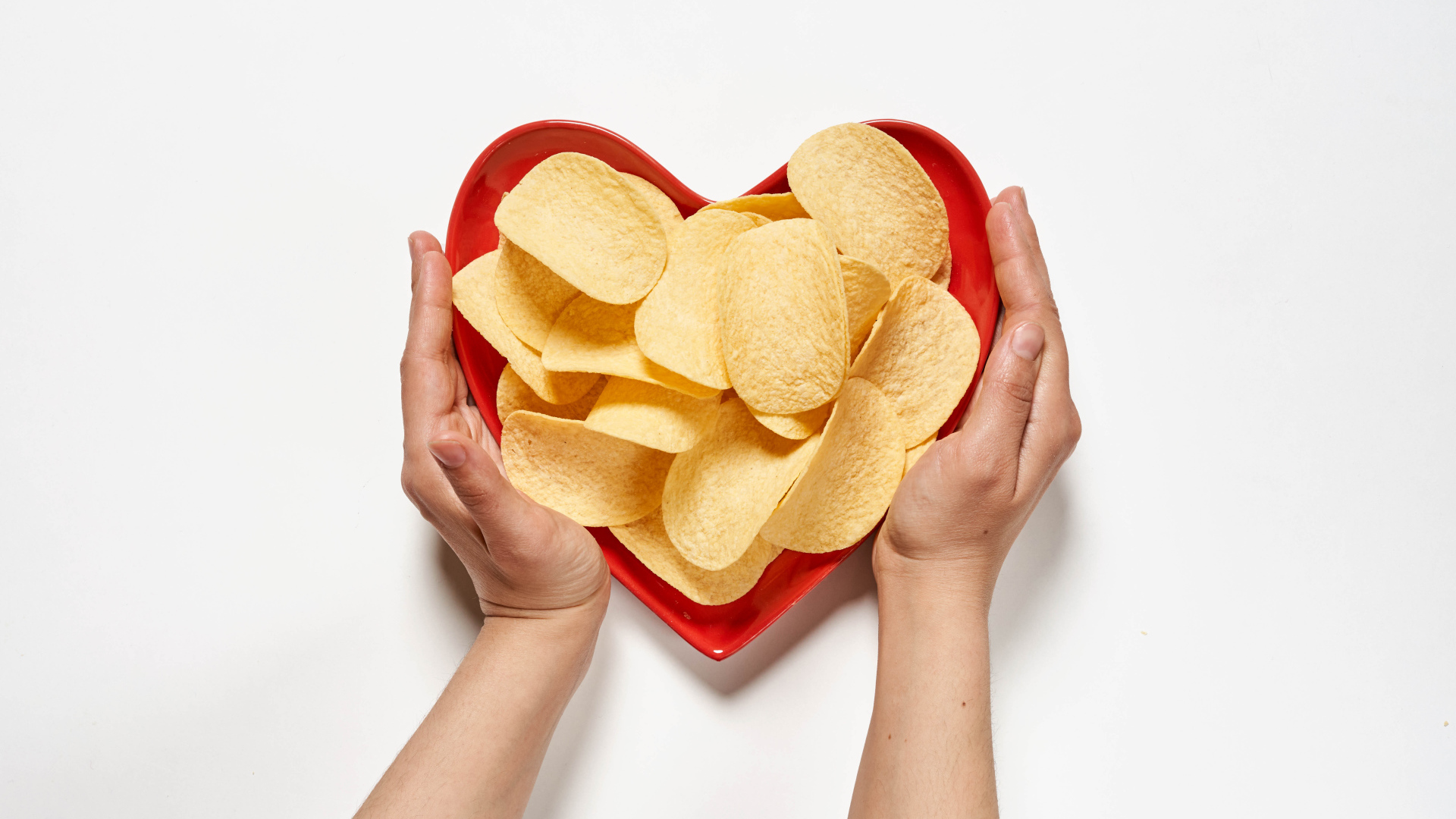 Чипсы в красной тарелке на белом фоне