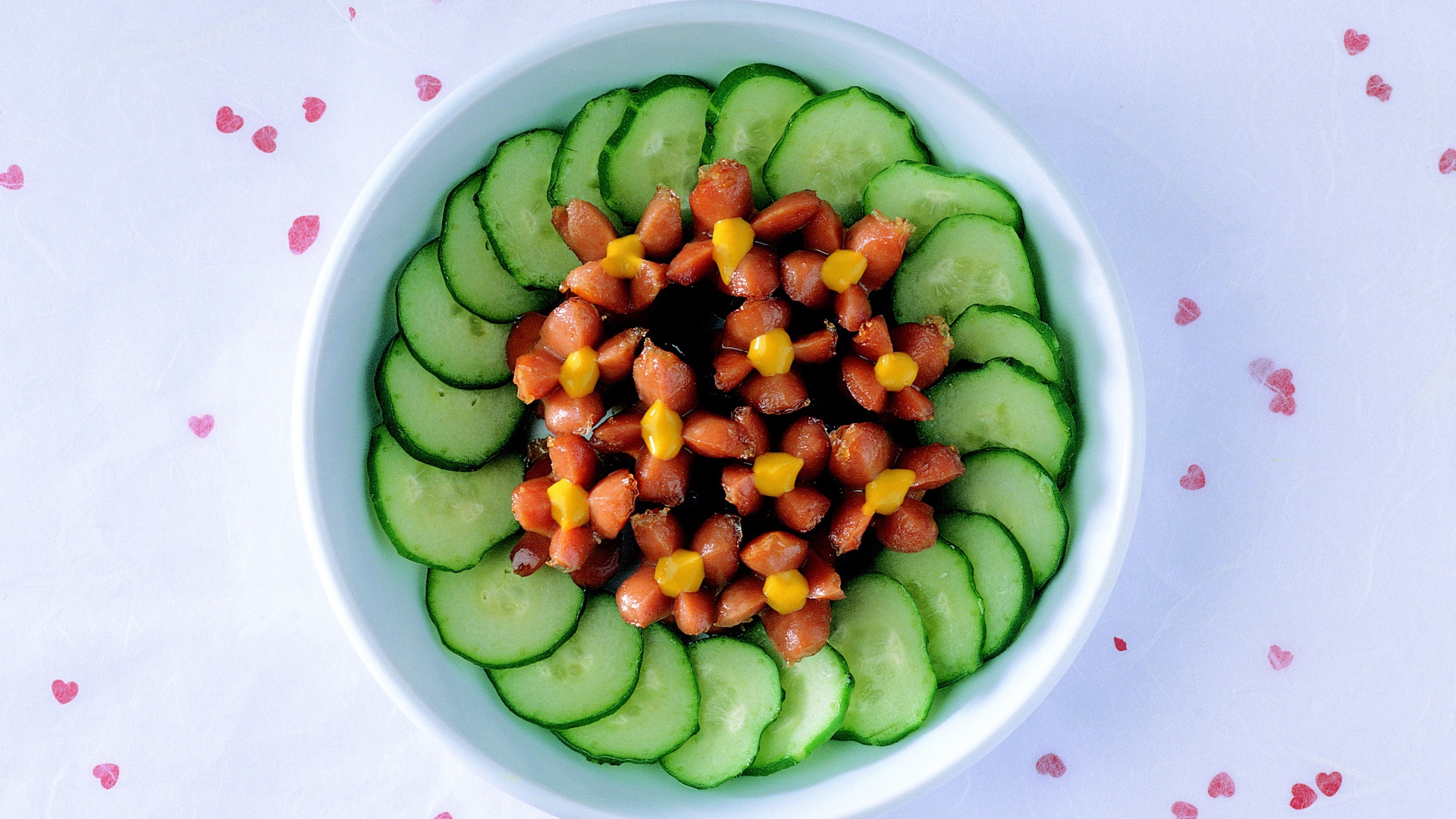 Огурцы с сосисками в тарелке на столе