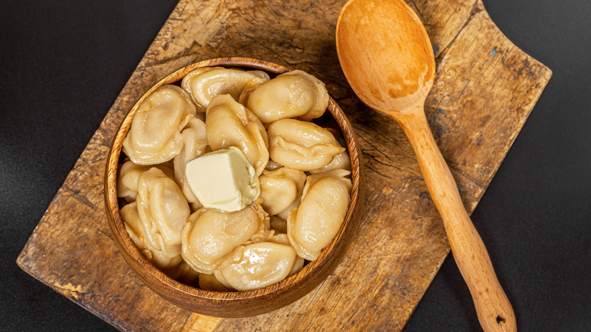 Пельмени в деревянной миске с маслом