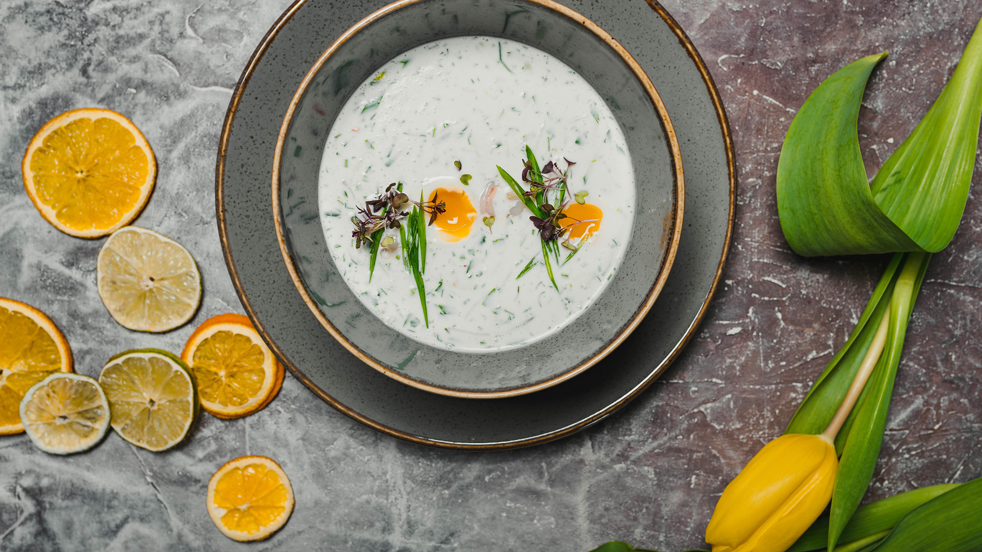 Окрошка на столе с лимонами и тюльпаном