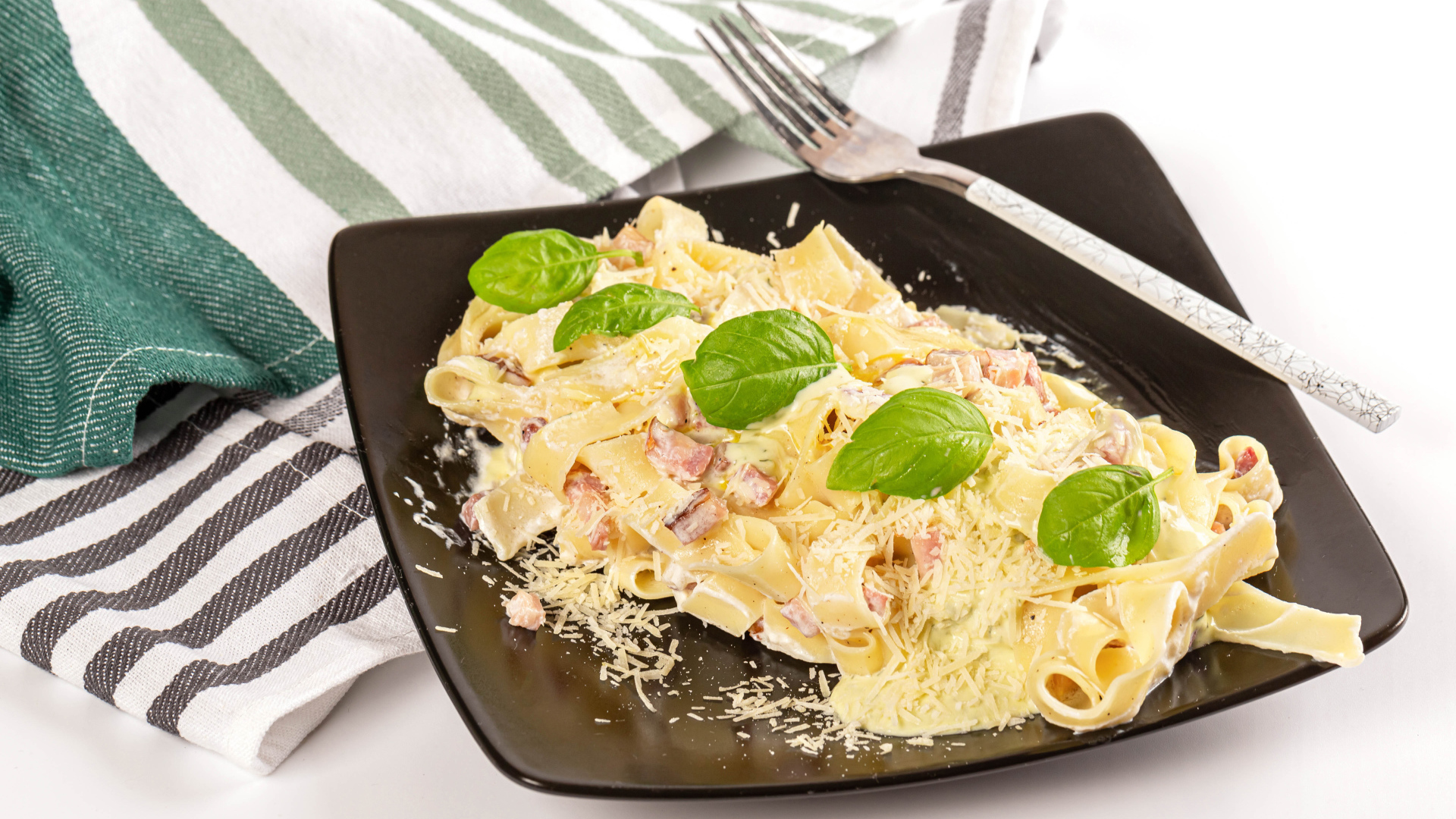 Макароны на тарелке с тертым сыром и кусочками мяса