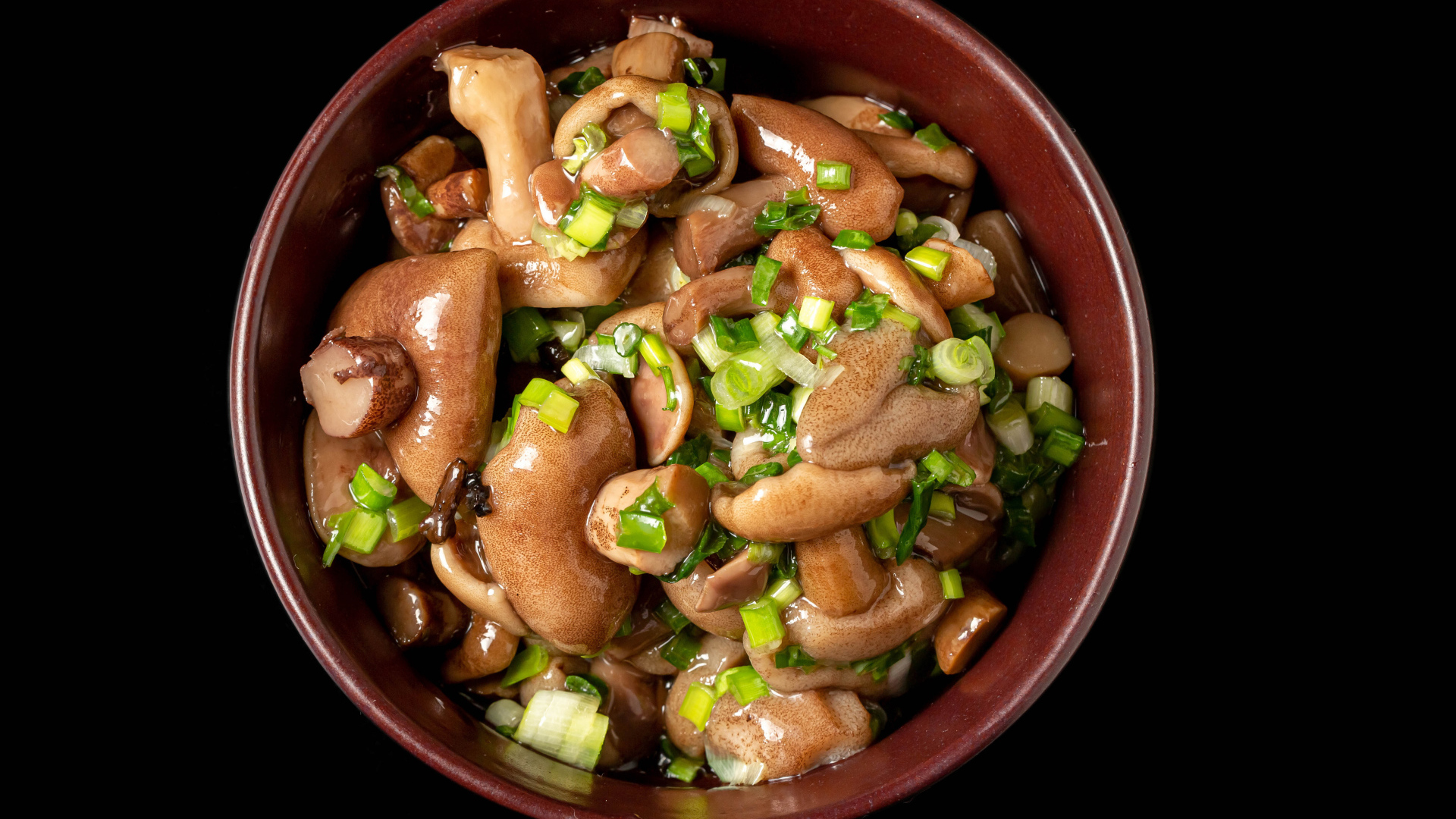 Маринованные маслята с зеленью в тарелке