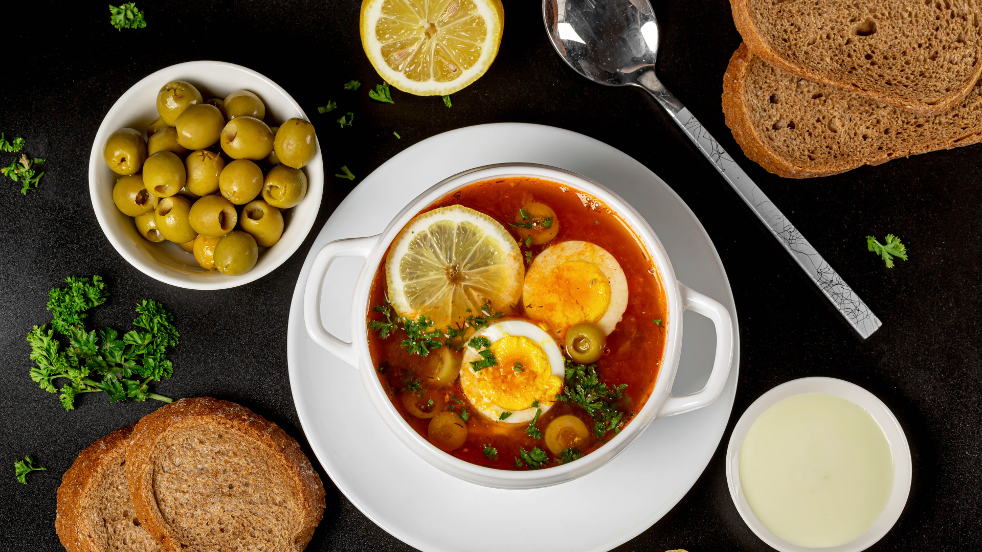 Солянка на столе  с хлебом и оливками 