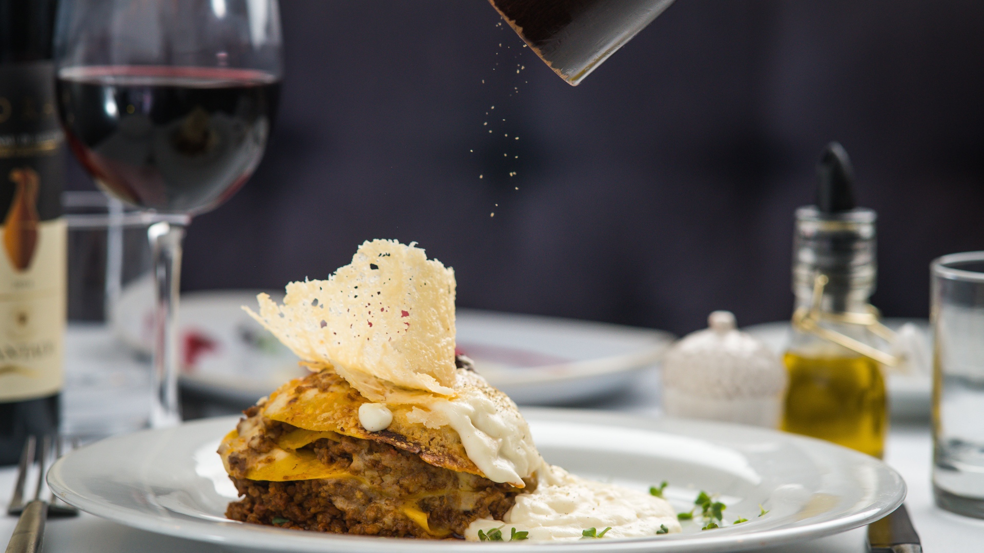 Кусок лазаньи посыпают перцем 