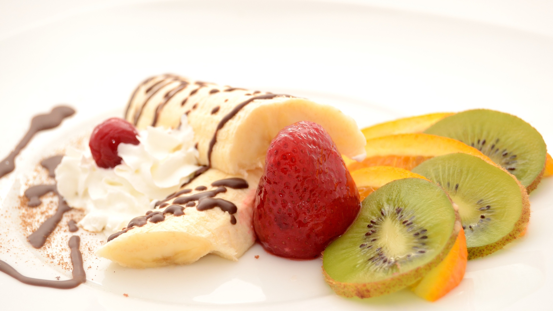 Бананы, киви и клубника на тарелке со сливками