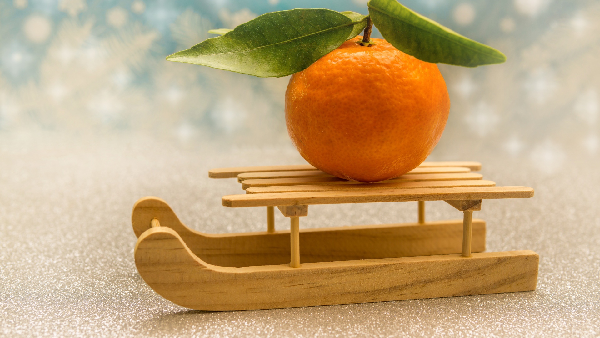 Большой оранжевый мандарин на маленьких санках