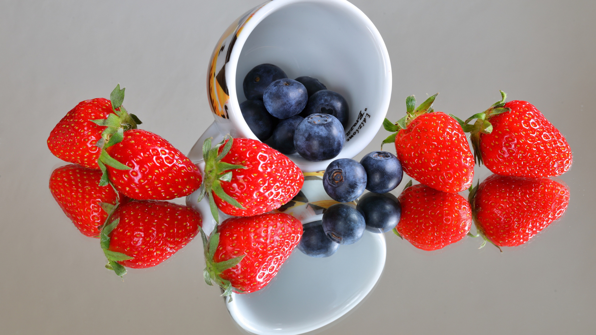 Чашка с ягодами черники и клубники на столе