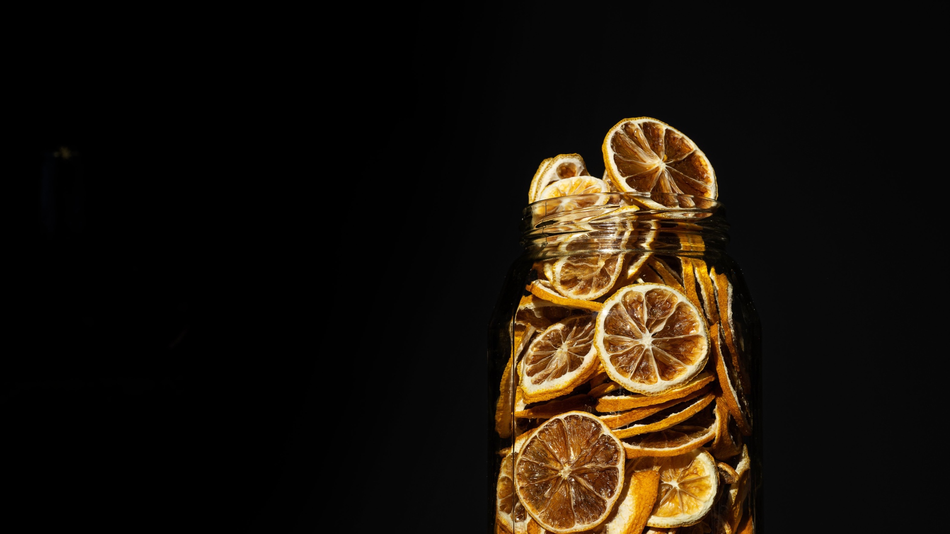 Сушеные лимоны в банке на черном фоне