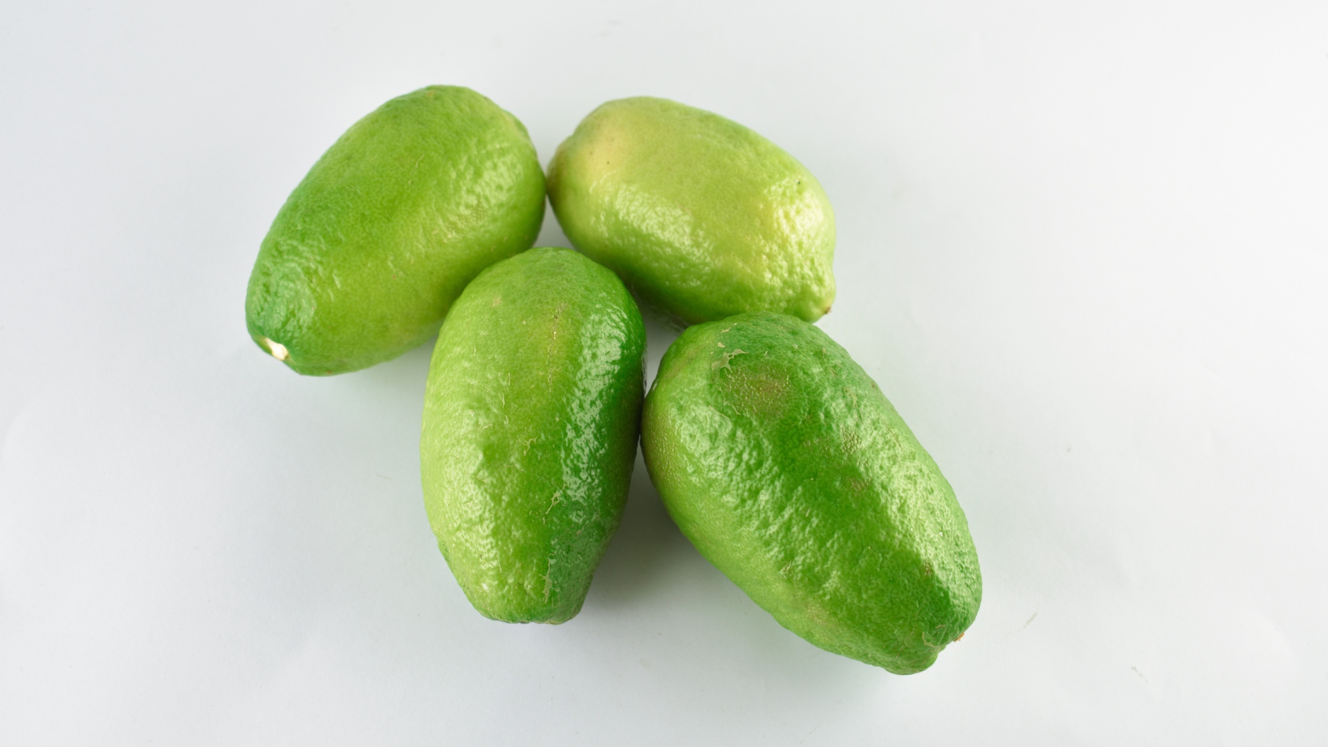 Четыре зеленых лимона на белом фоне