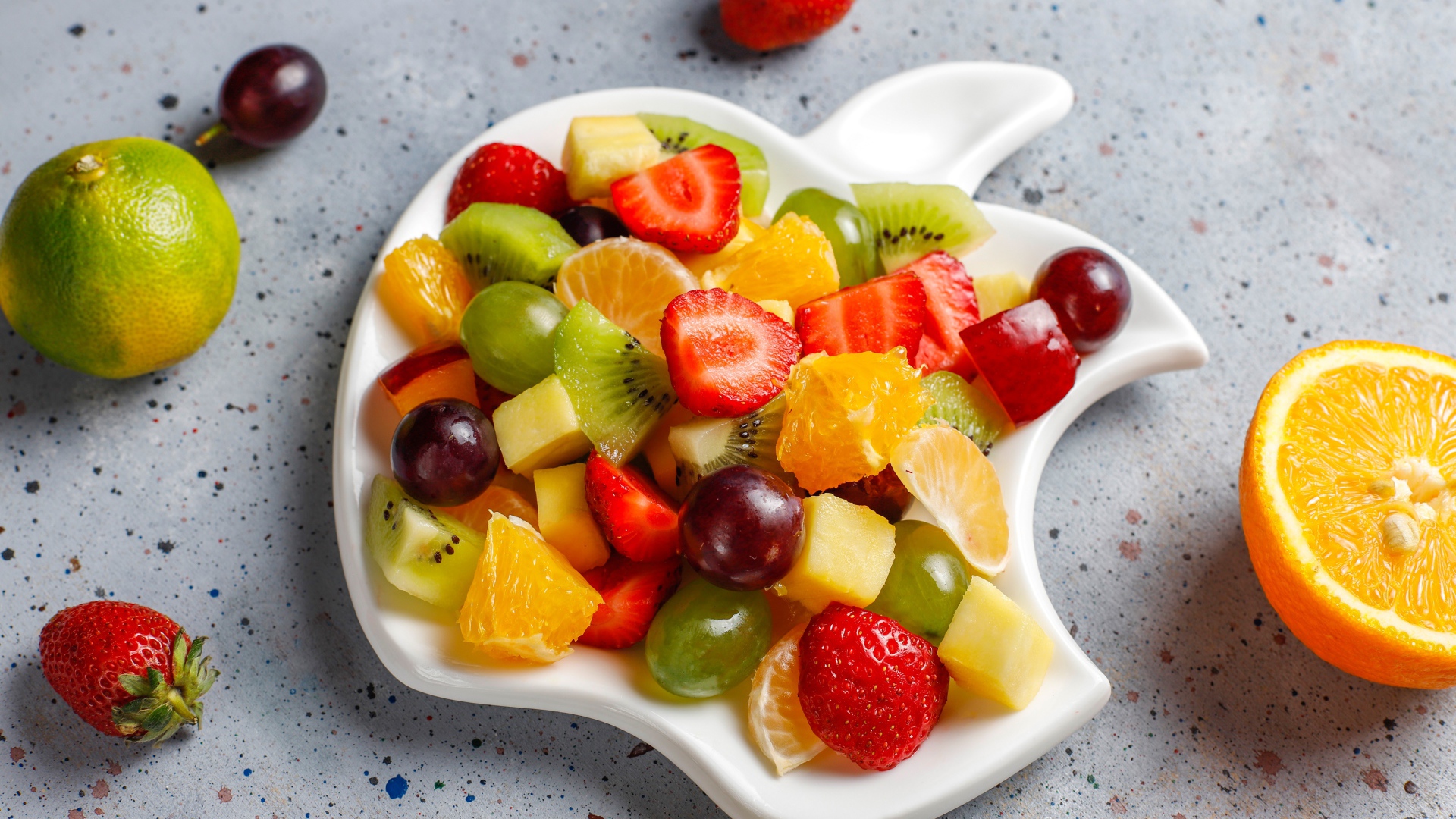 Фруктовый салат на белой тарелке на столе 