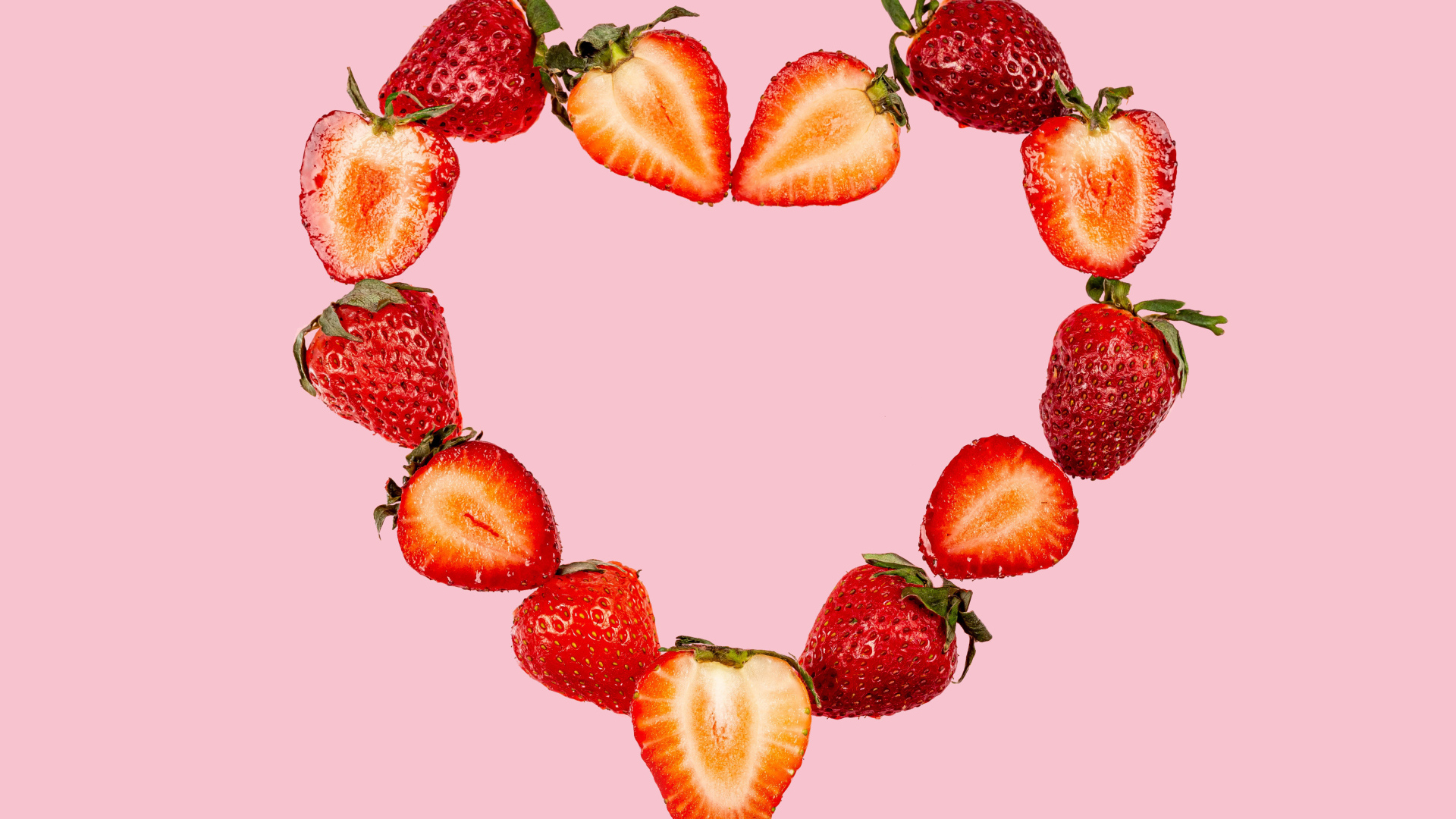 Сердце из клубники на розовом фоне 