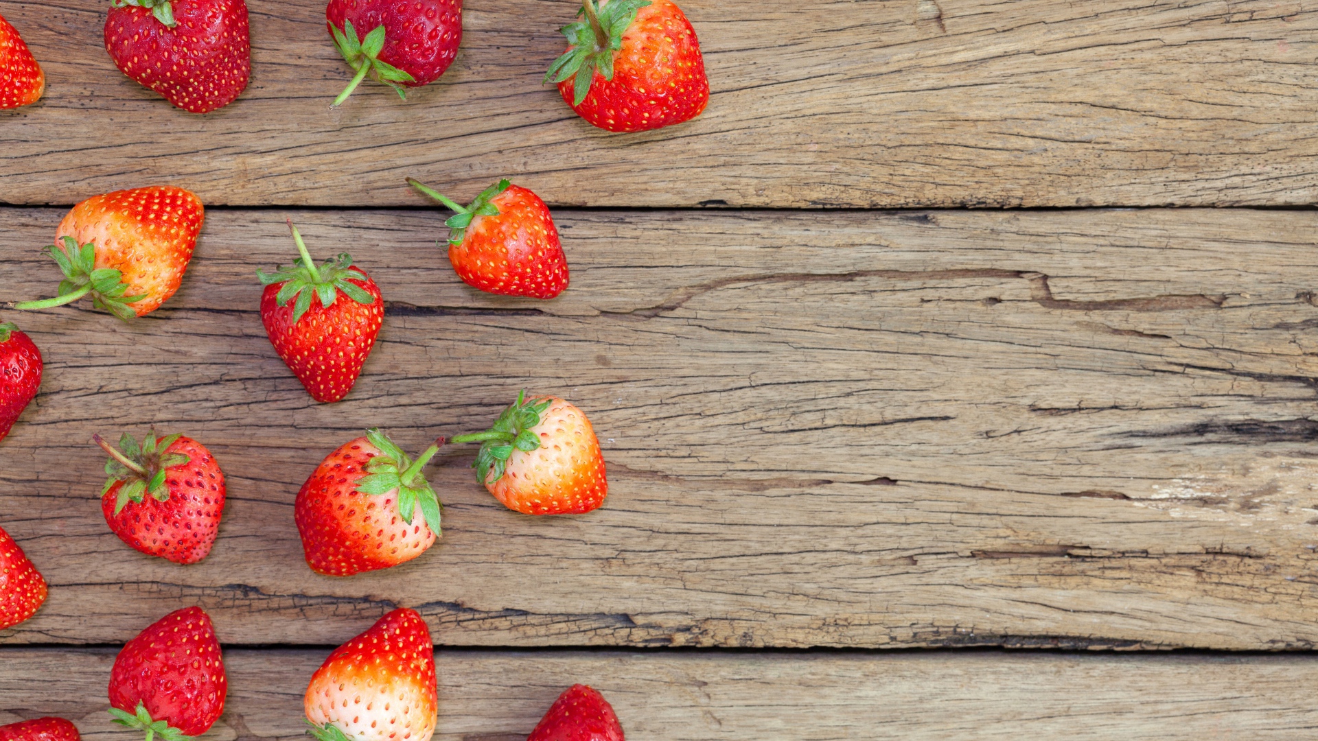 Спелая красная клубника лежит на деревянном столе