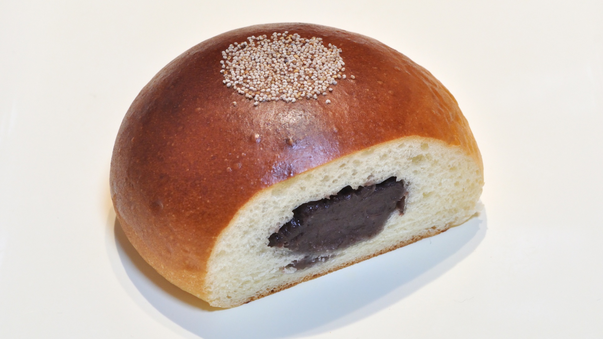 Свежая румяная булочка с вареньем на белом фоне