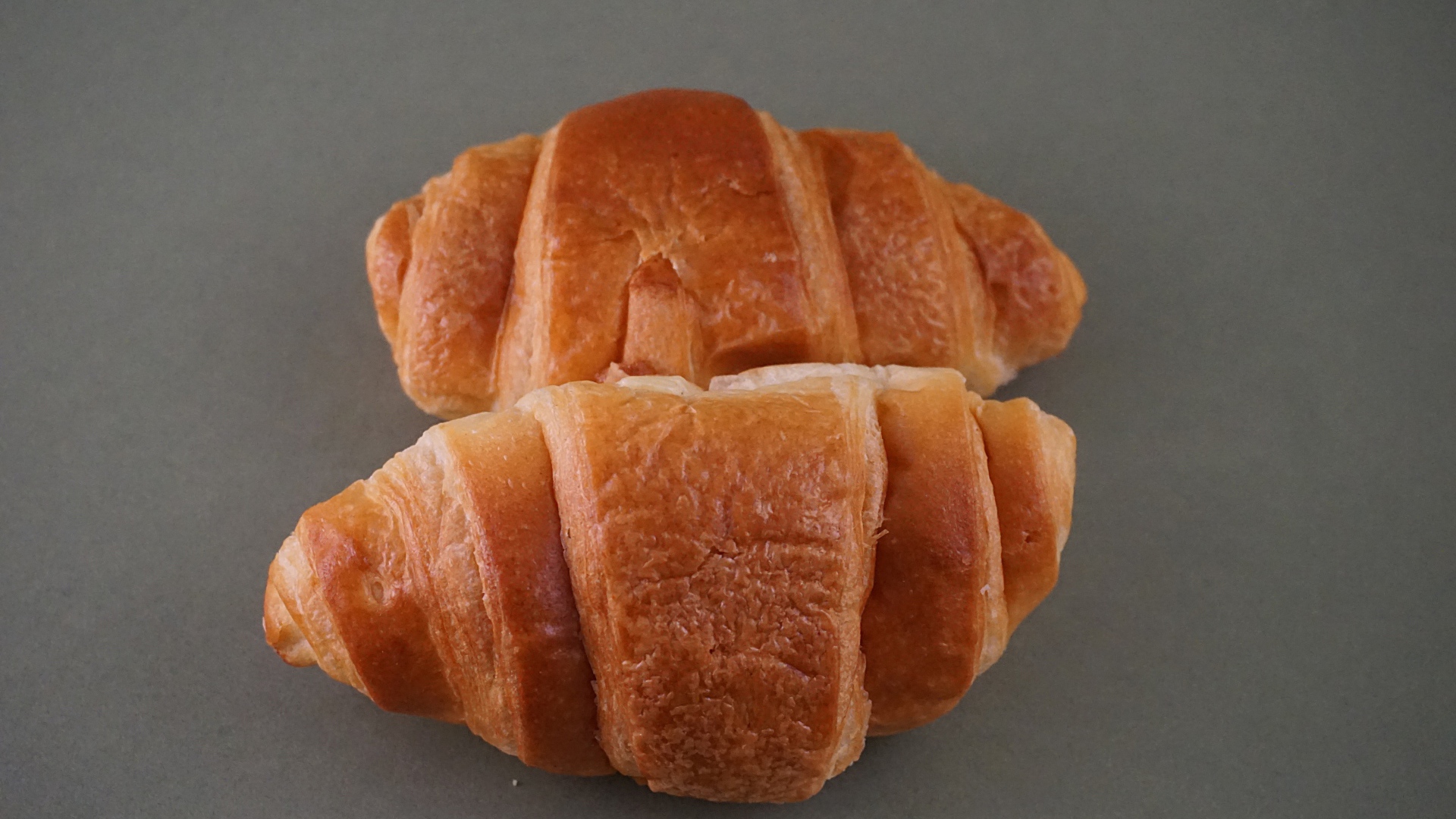 Два свежих круассана на серой поверхности