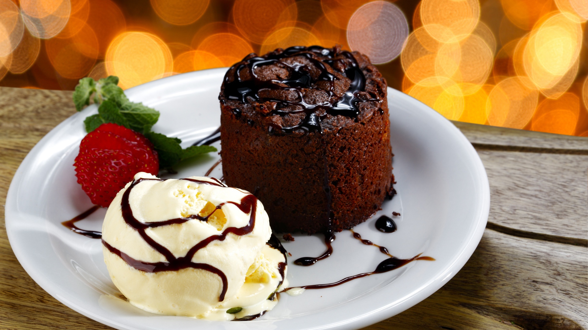 Шоколадный десерт с мороженым и клубникой на белой тарелке 