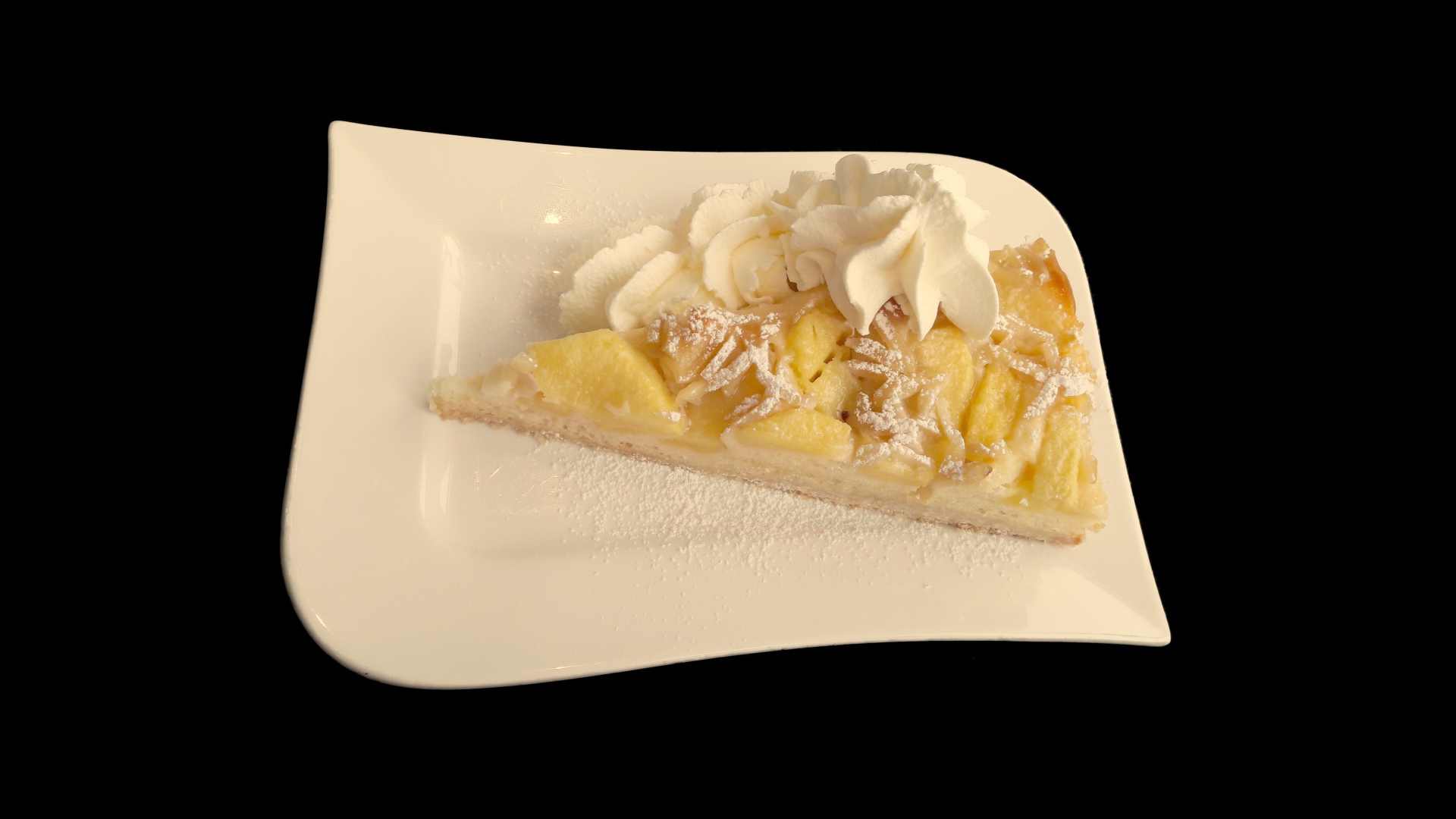 Кусок пирога с фруктами в белой тарелке на черном фоне