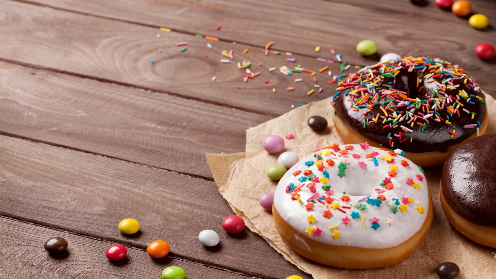 Сладкие пончики с глазурью на столе с конфетами