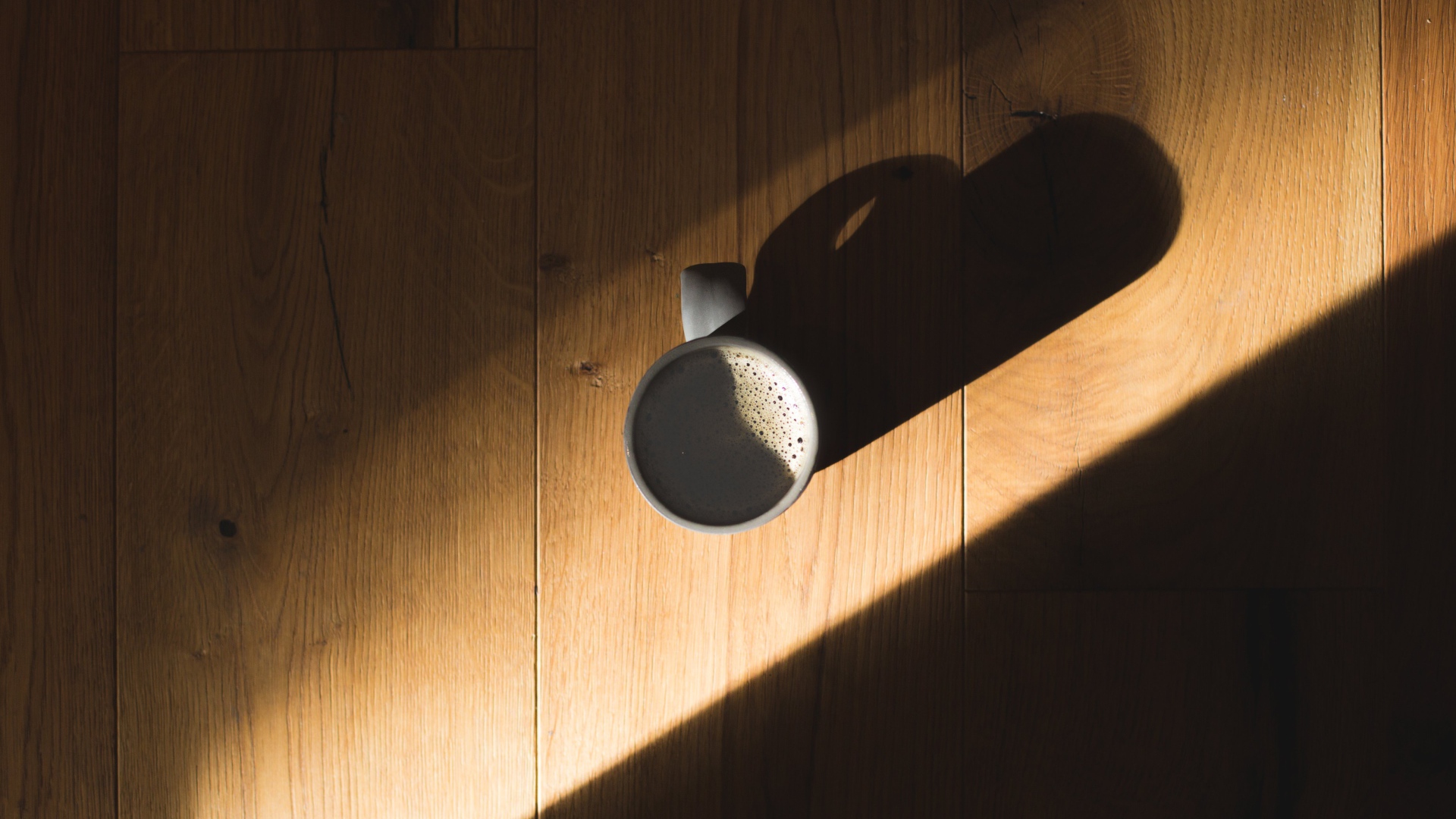 Чашка кофе стоит на столе в лучах солнца