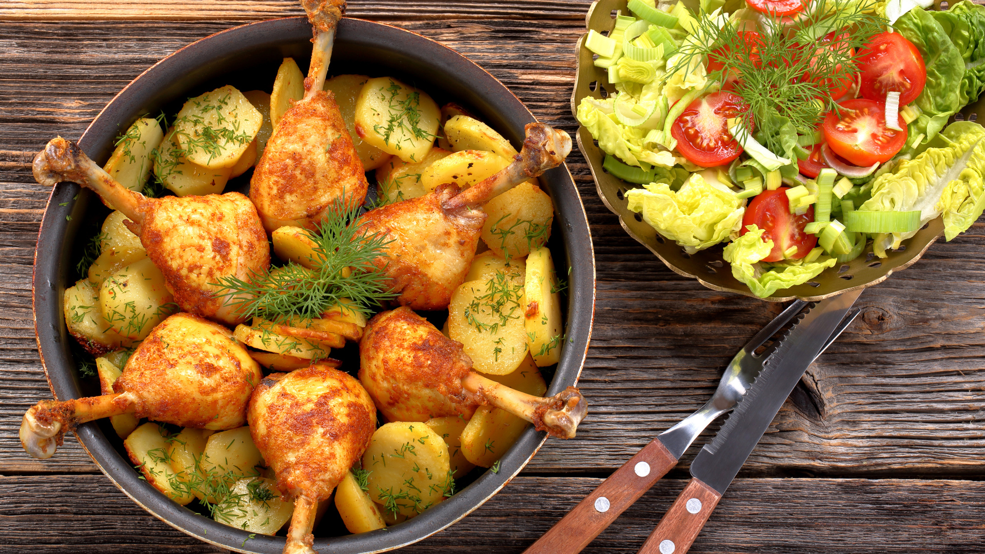 Fried chicken legs with potatoes on a table with salad