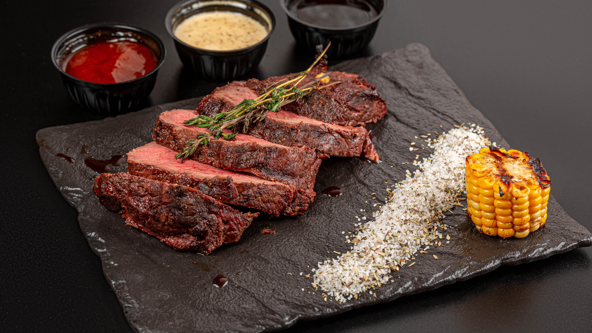 Кусок запеченного мяса на доске с кукурузой и специями 