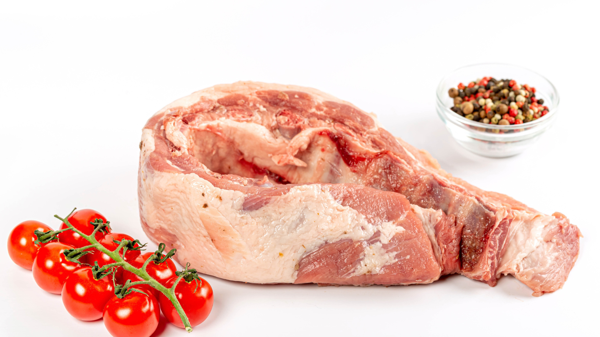 Кусок мяса на белом фоне с помидорами и специями 