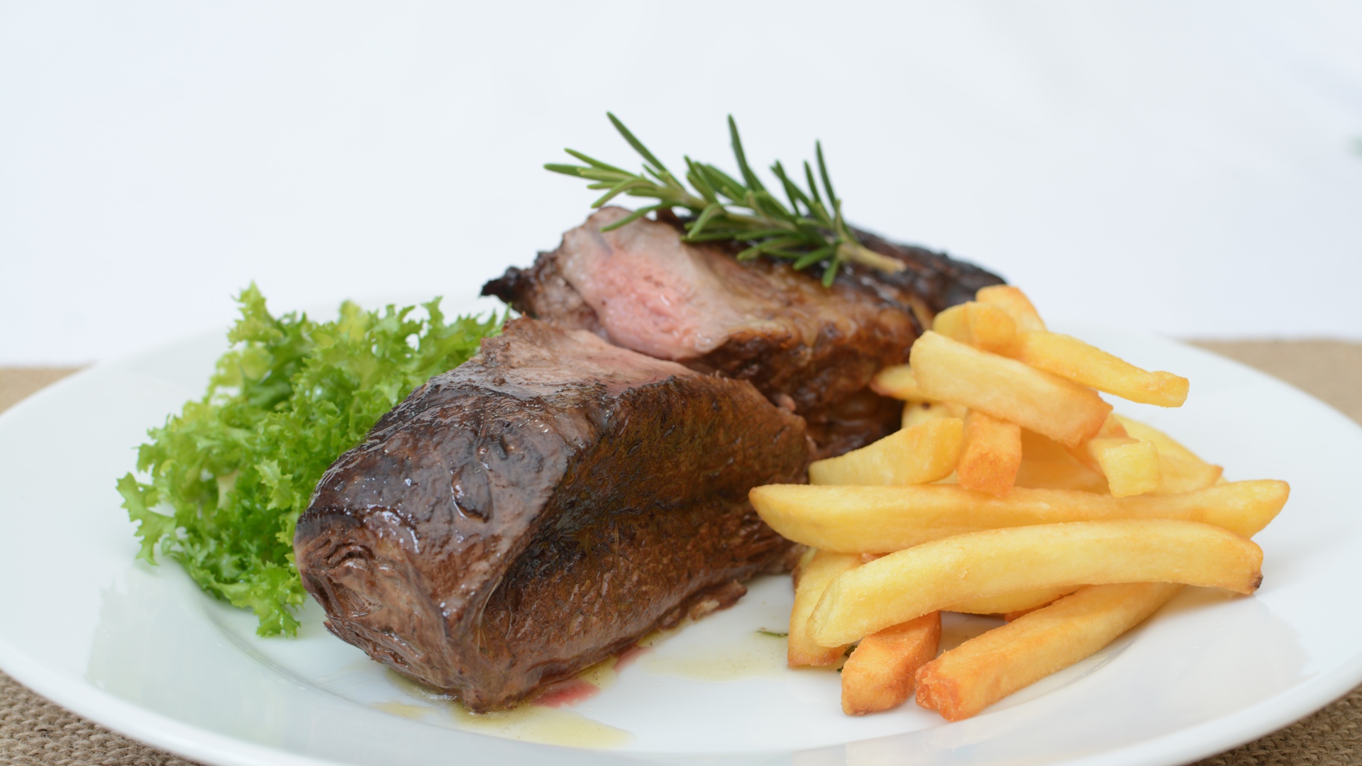 Два куска мяса на тарелке с картофелем фри 