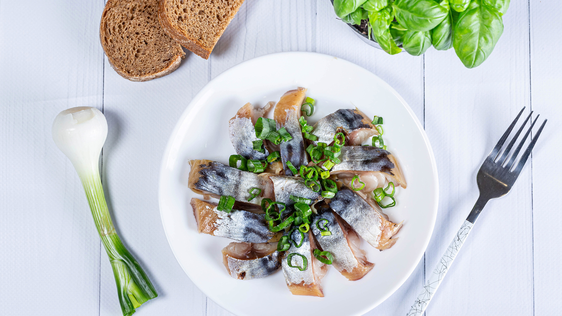 Куски скумбрии на столе с луком, хлебом и базиликом