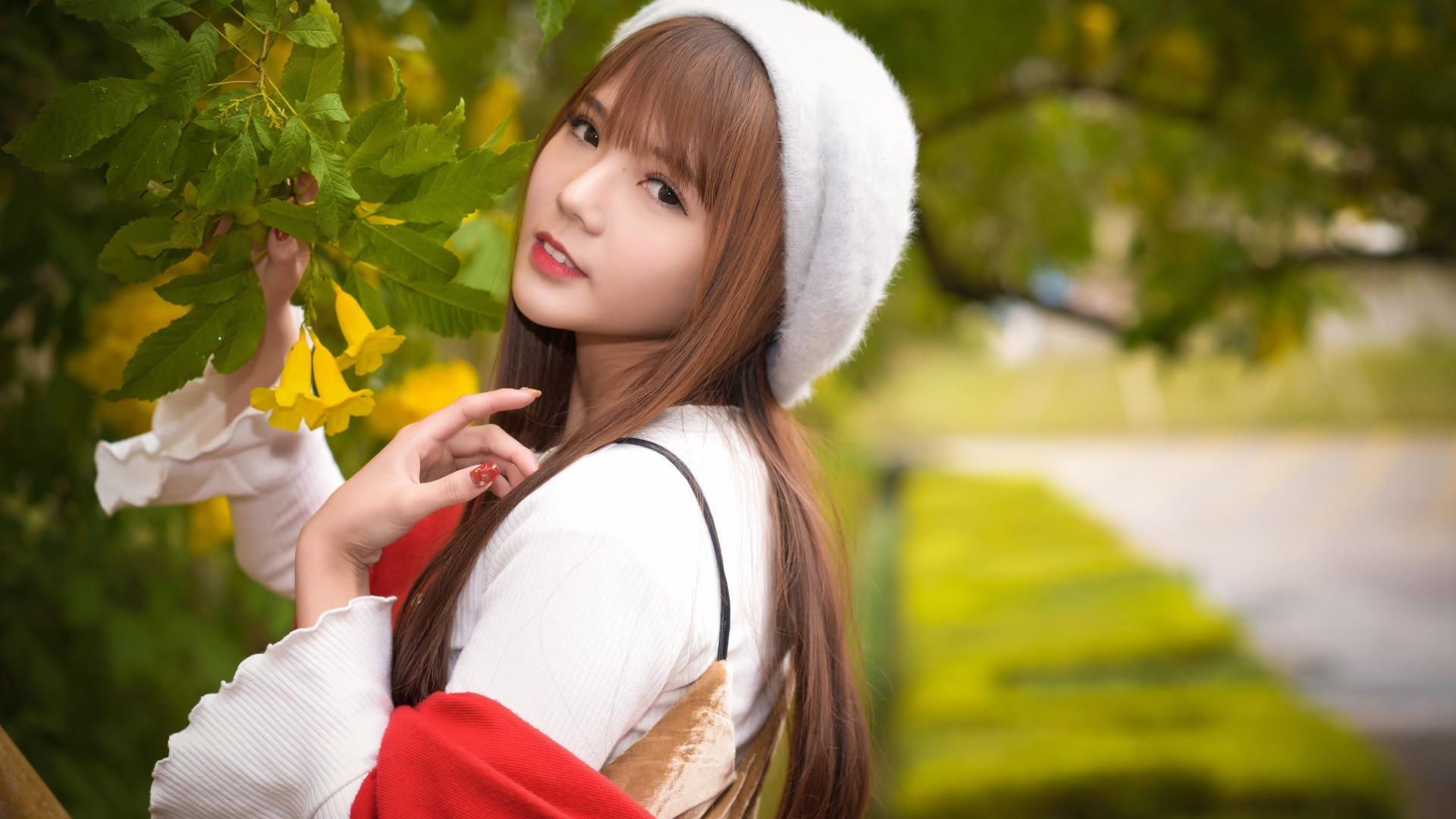 Девушка в берете стоит у куста с желтыми цветами