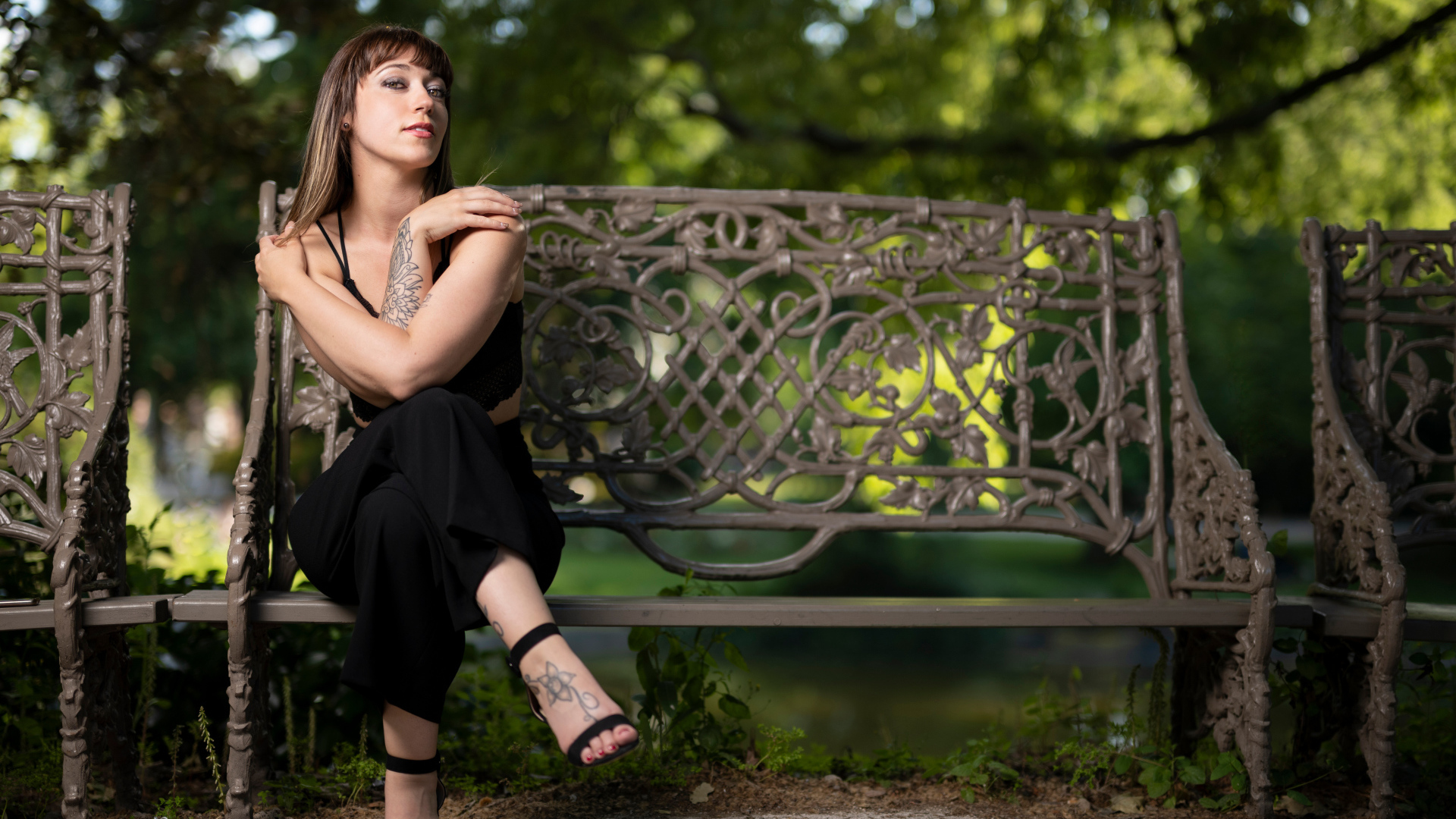 Девушка в черном костюме сидит на лавке 