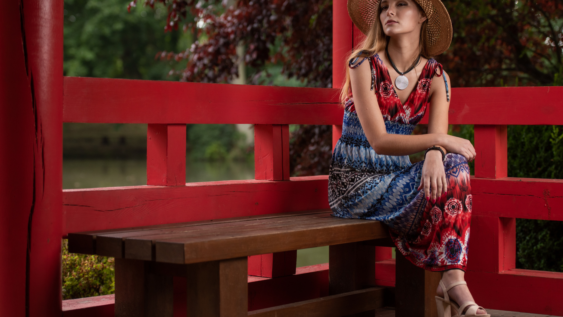 Молодая девушка в платье сидит на лавке 