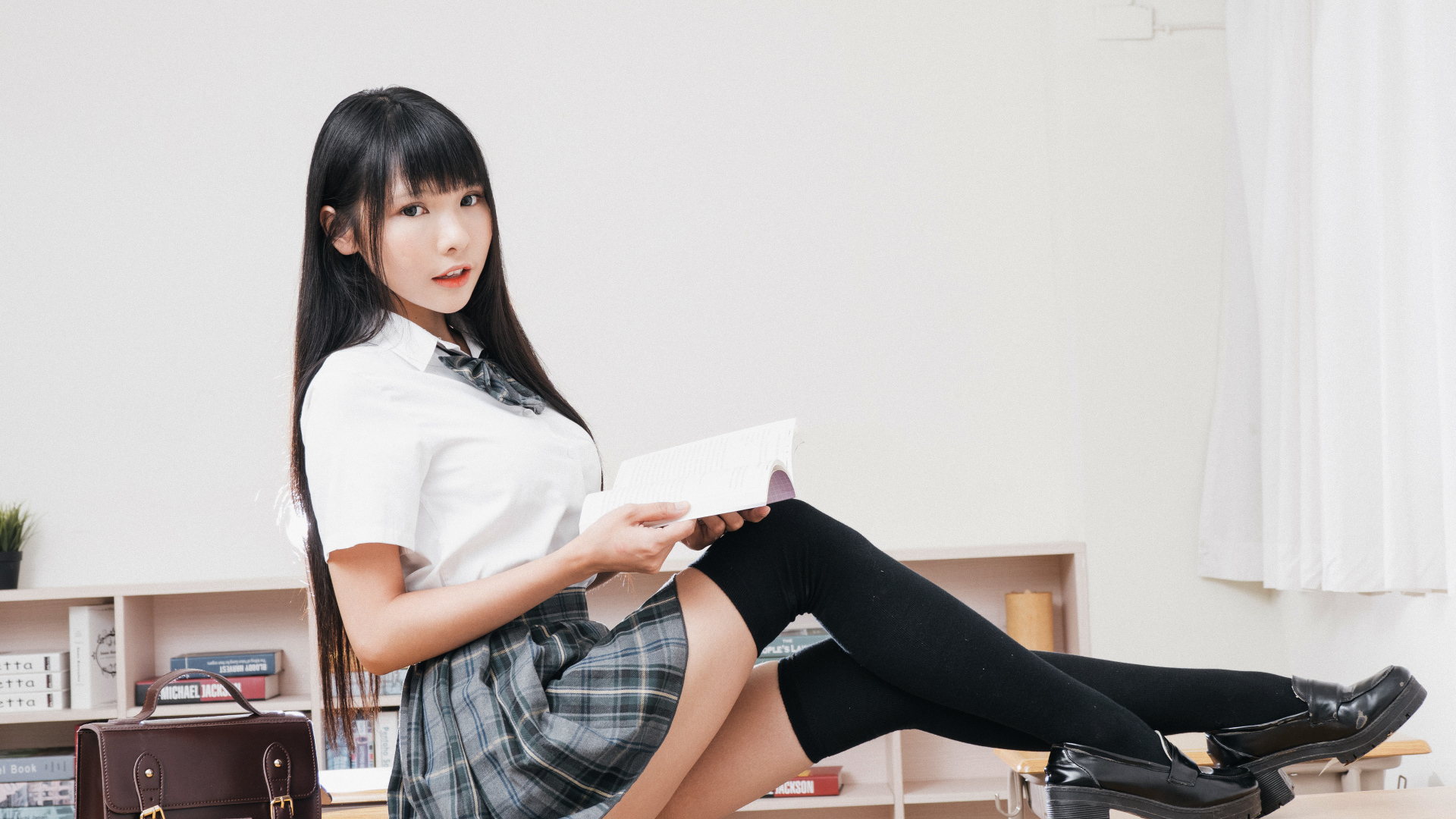 Девушка азиатка в костюме школьницы на парте 