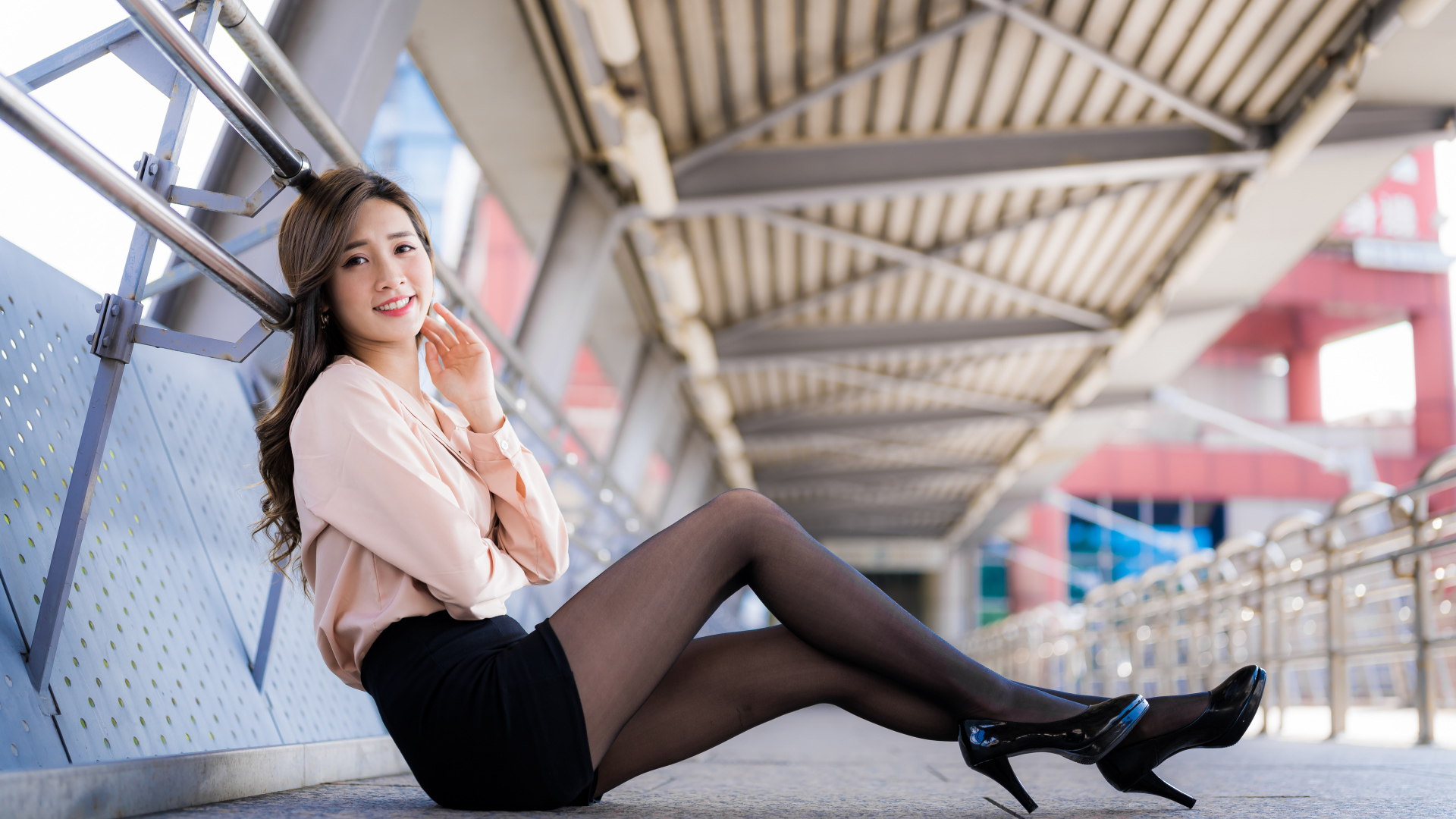 Девушка азиатка в черной юбке сидит в переходе 