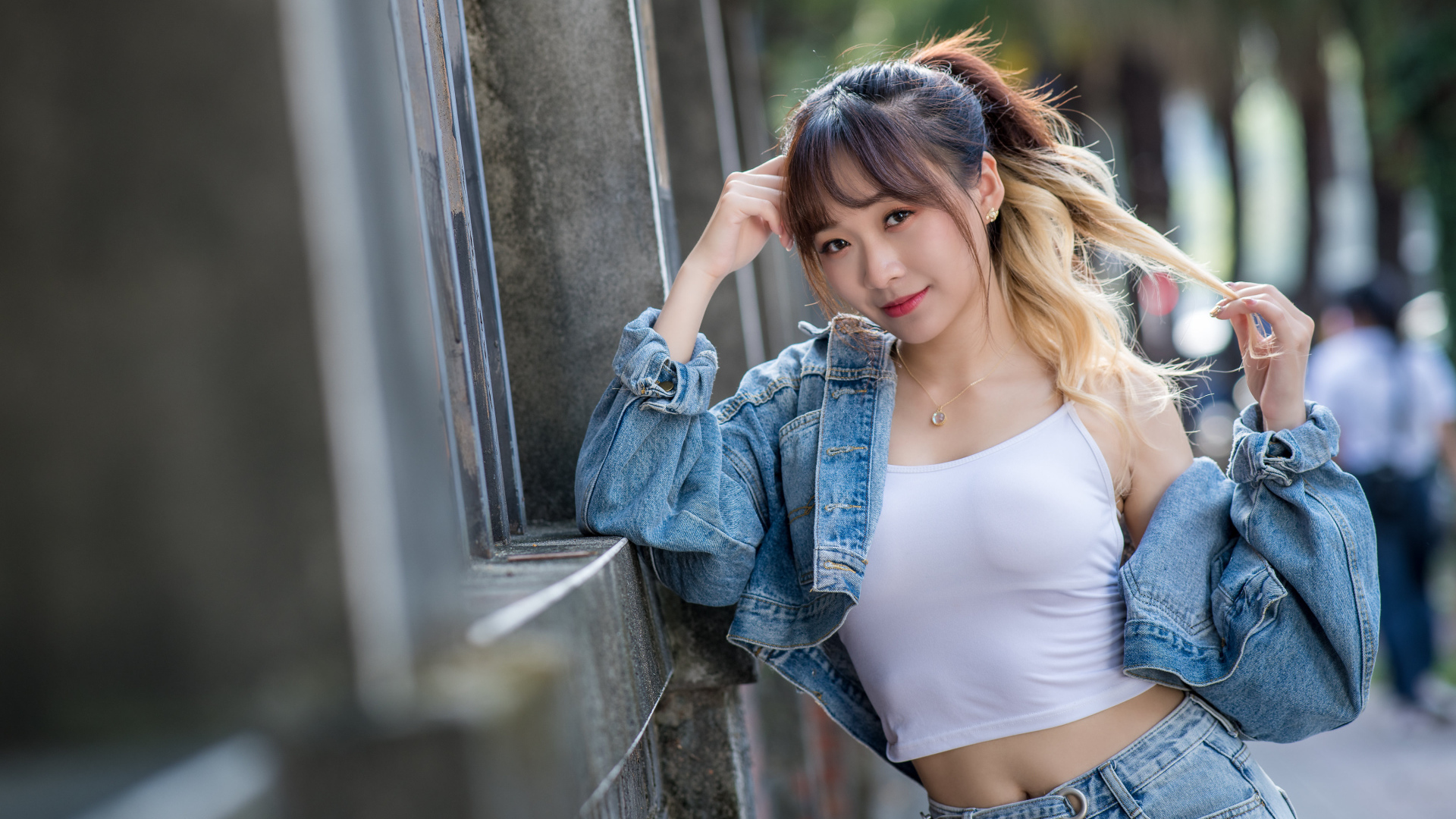 Девушка азиатка в джинсовой куртке у забора 