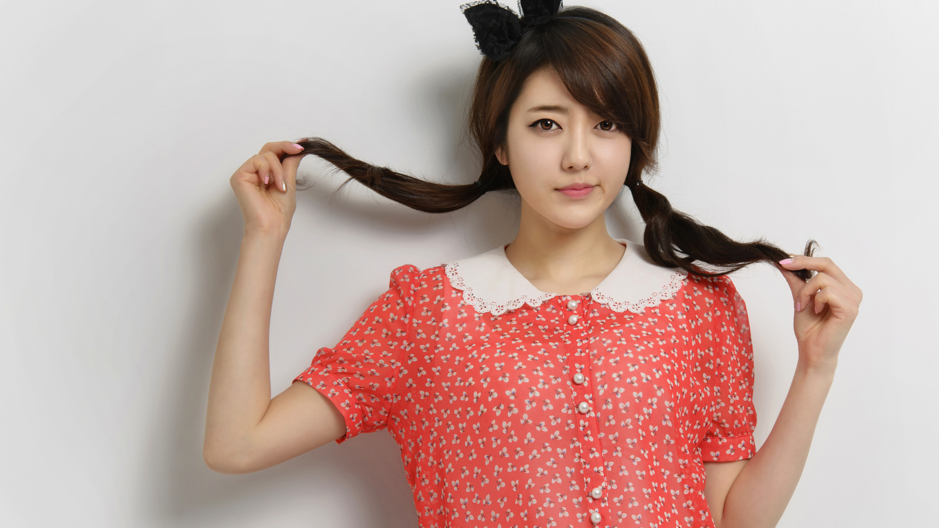 Девушка азиатка в платье стоит у стены 