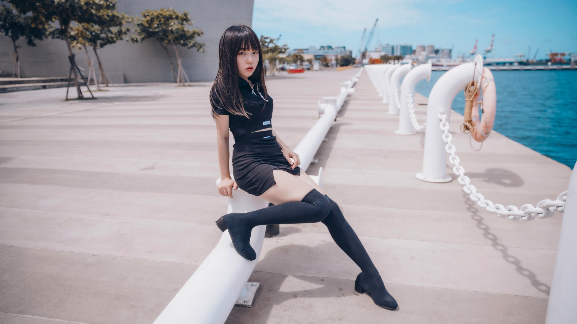 Девушка азиатка в черном костюме на пристани 