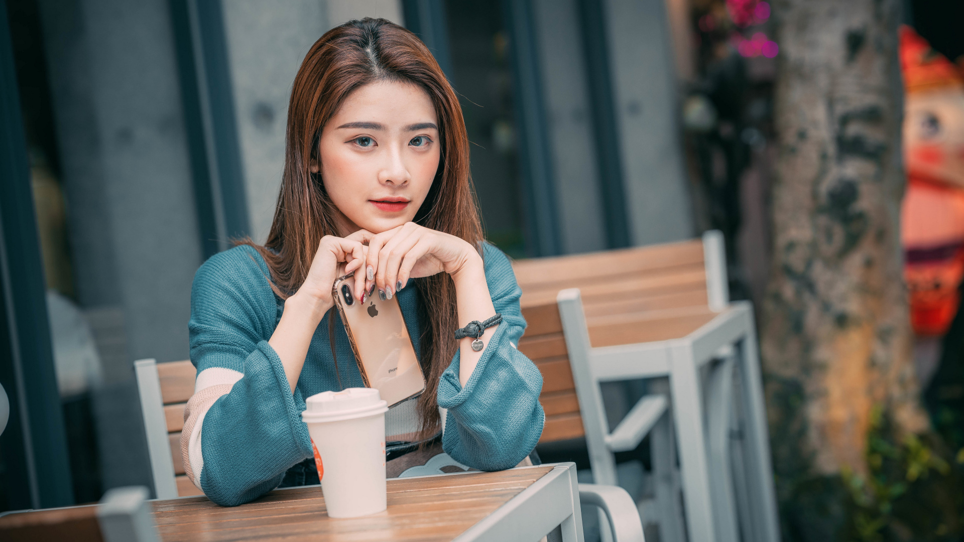 Девушка азиатка сидит за столом в кафе с телефоном 