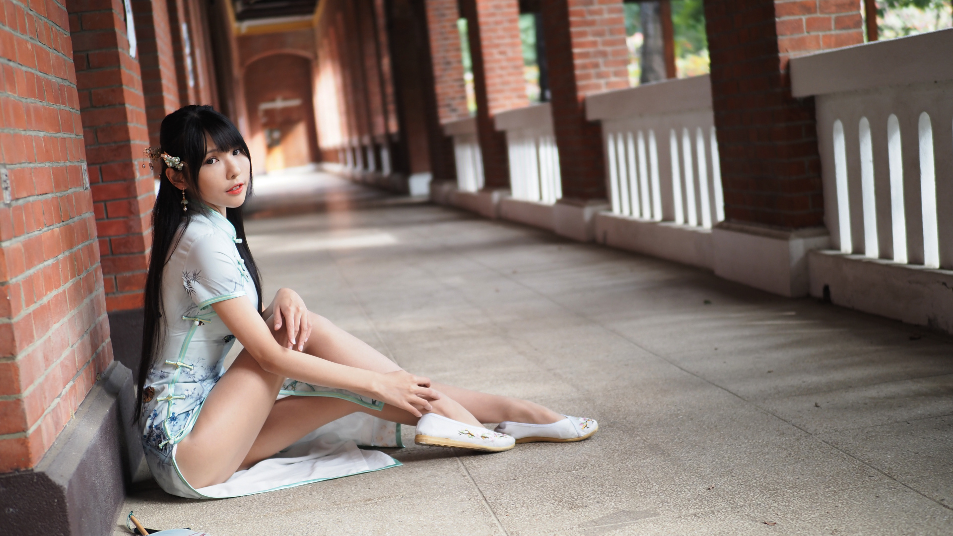 Девушка азиатка сидит на холодном полу у стены