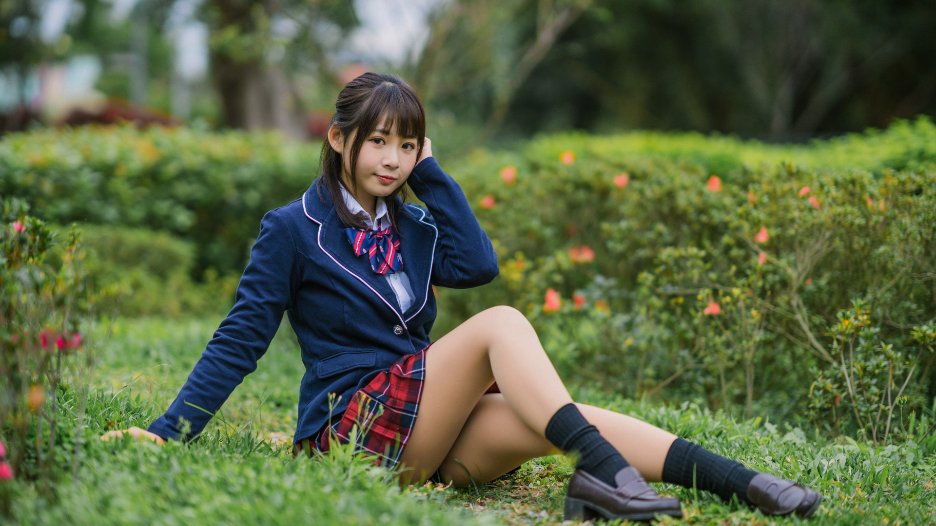 Азиатская школьница сидит на траве