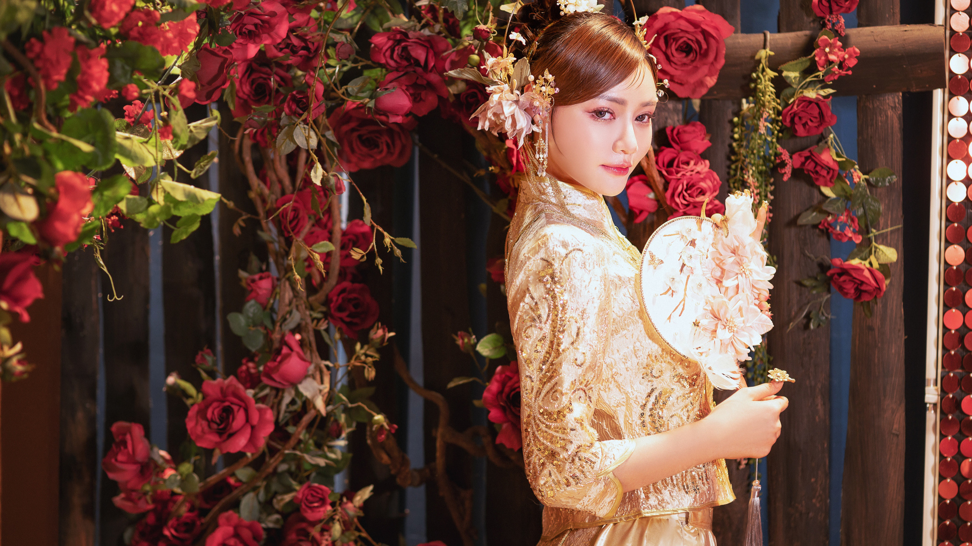 Азиатка в красивом национальном костюме у куста роз