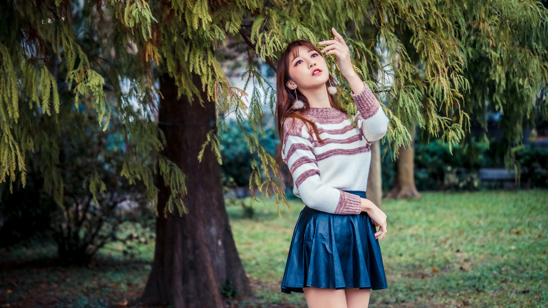 Красивая девушка азиатка стоит у дерева в парке