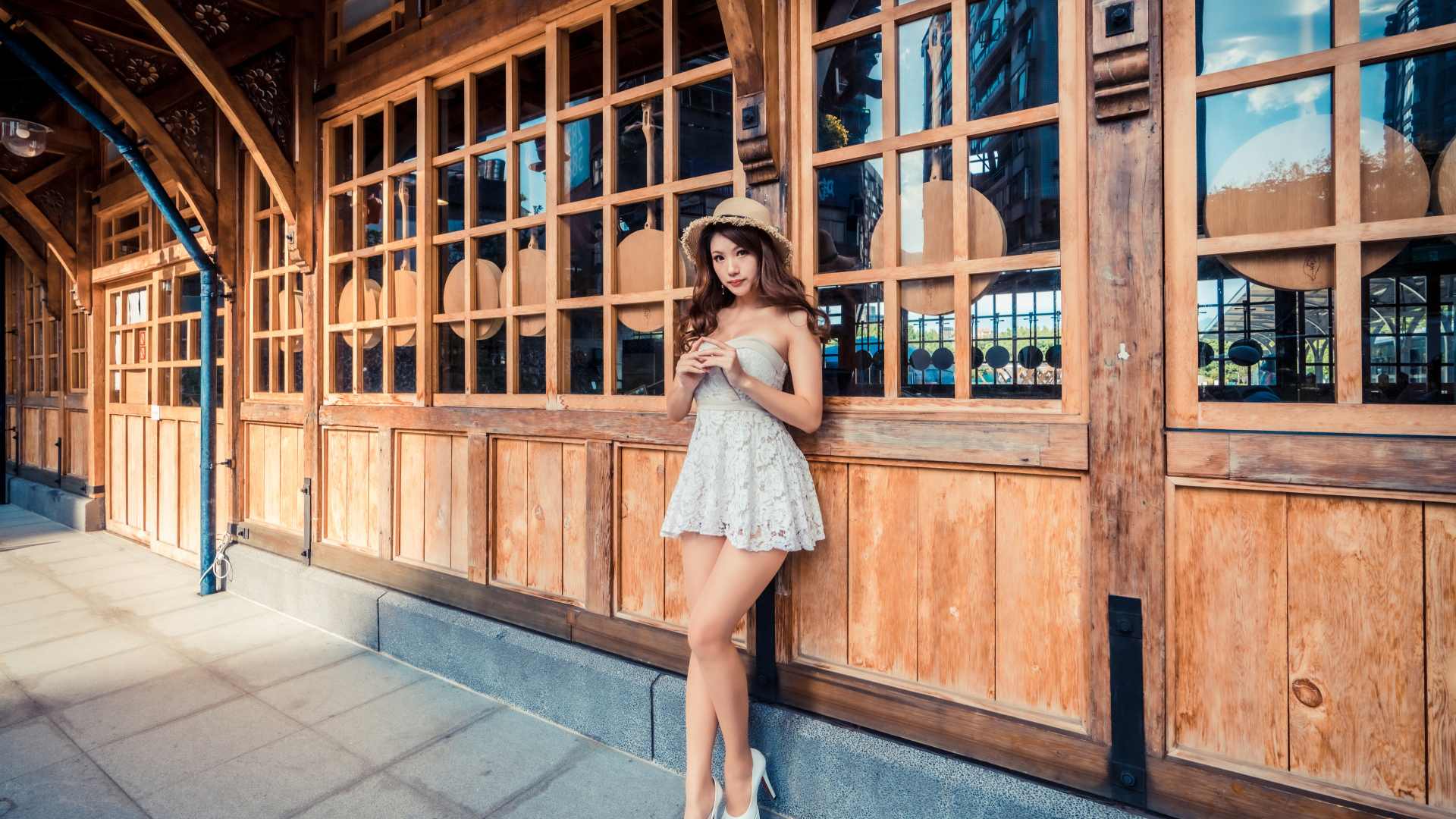 Красивая девушка азиатка стоит у стены с большими окнами