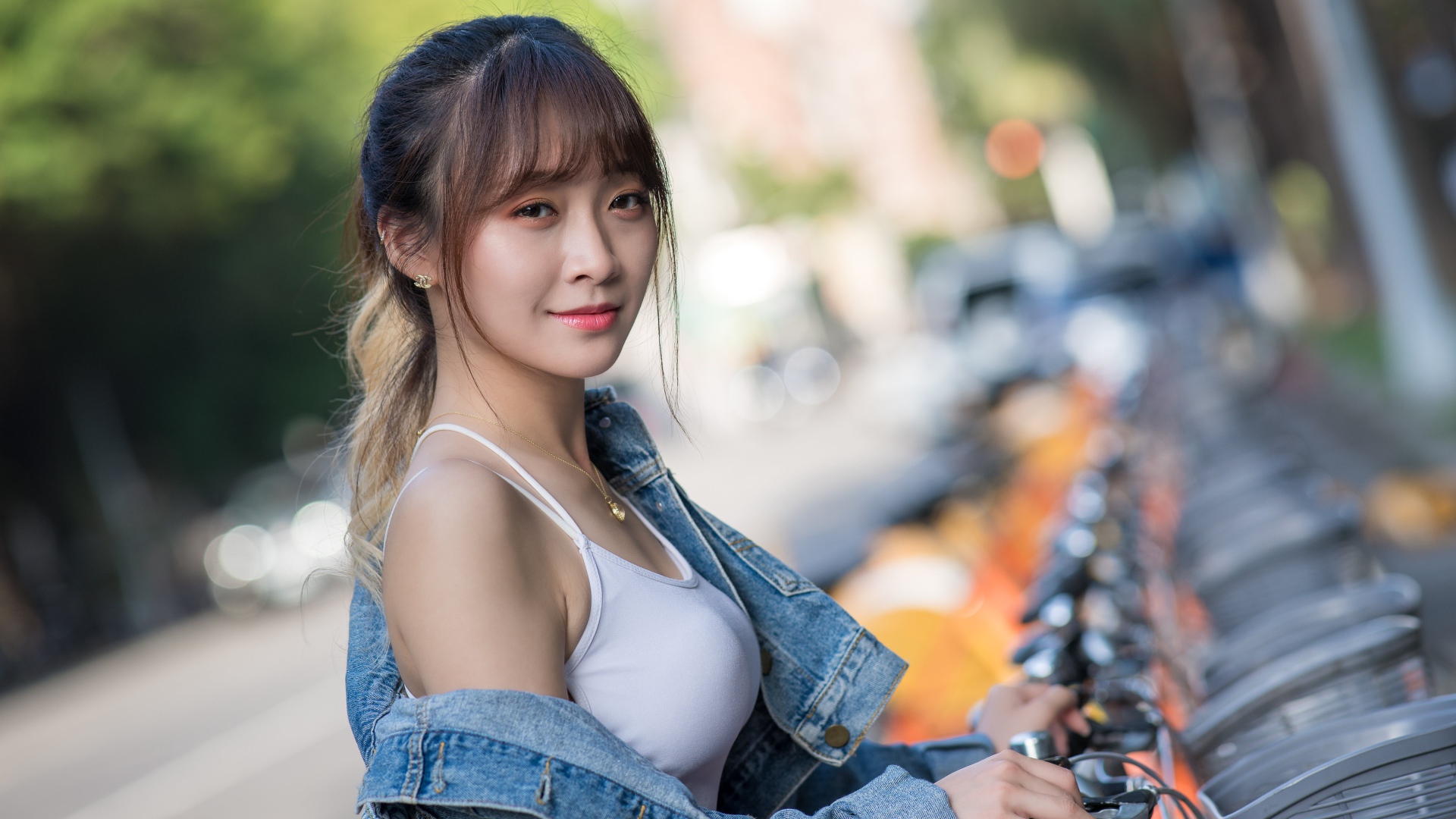 Красивая азиатка в джинсовой куртке с велосипедом