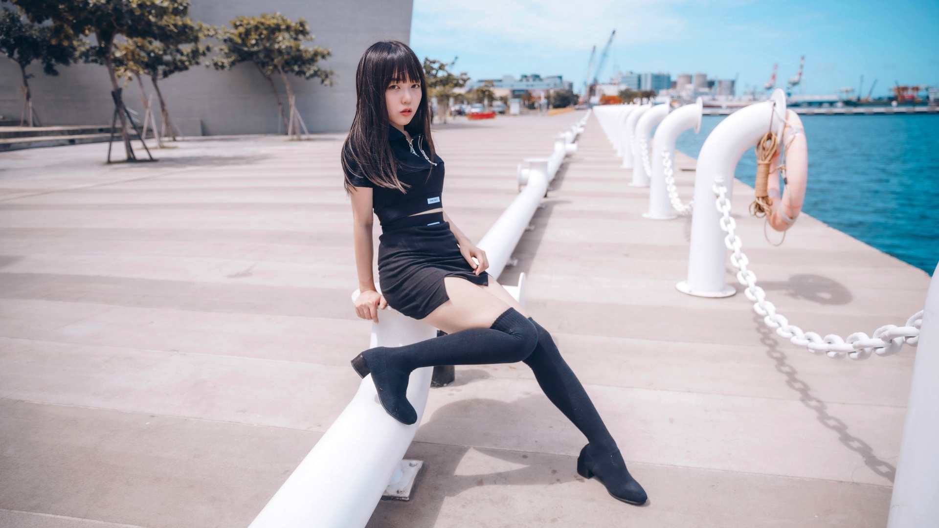 Красивая девушка азиатка в черных сапогах на причале