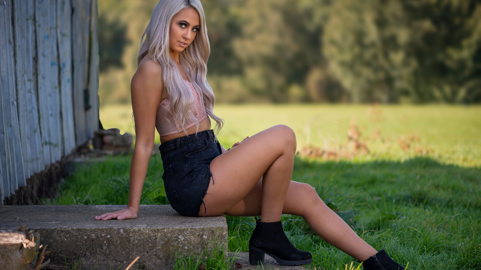 Красивая блондинка в черных шортах сидит на ступеньках 