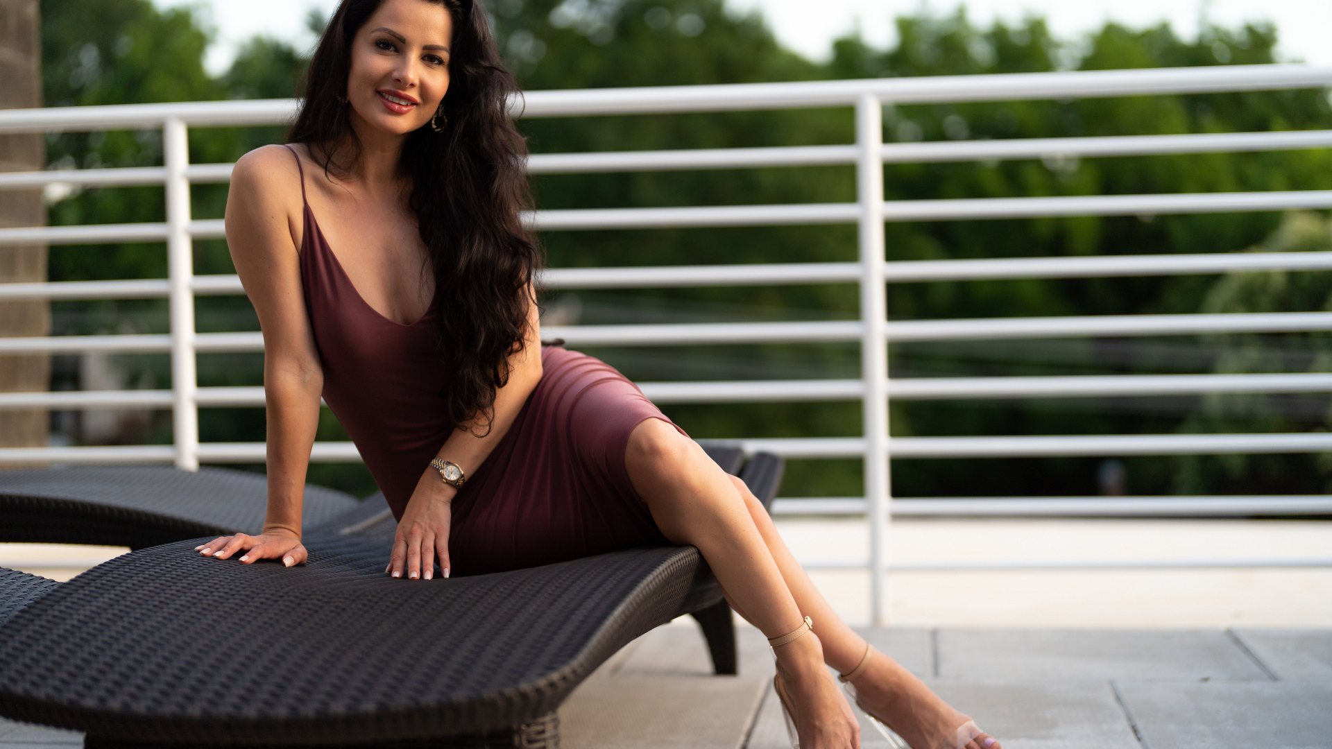 Красивая брюнетка в платье сидит на диване 