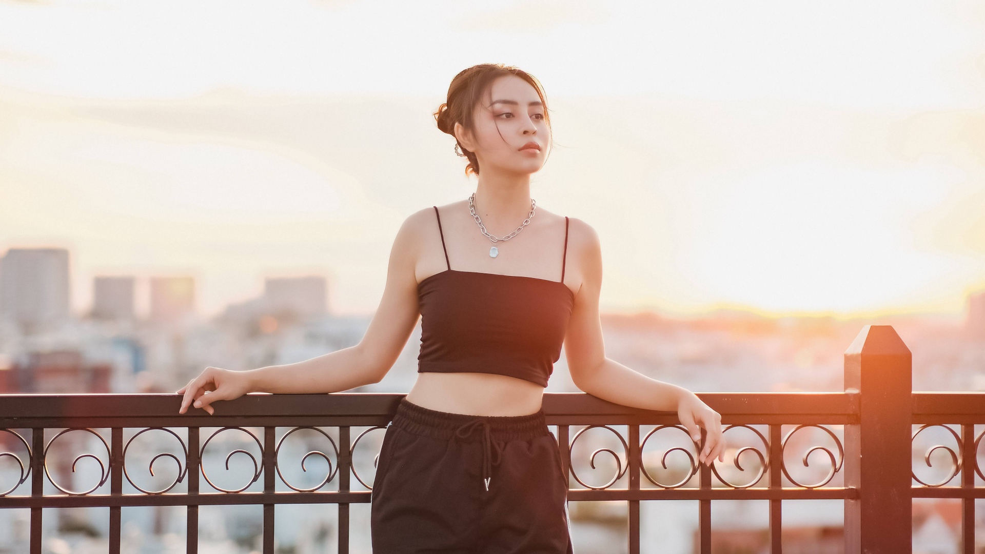 Красивая девушка в черном костюме на мосту в лучах солнца