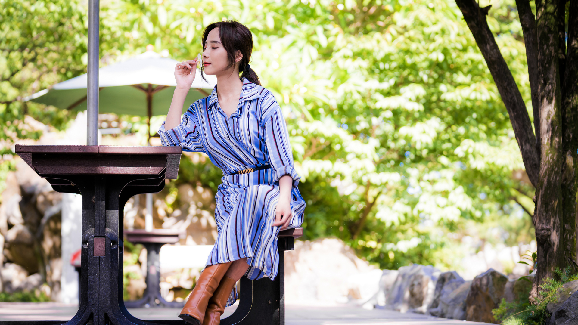 Красивая девушка в платье сидит за столиком в парке