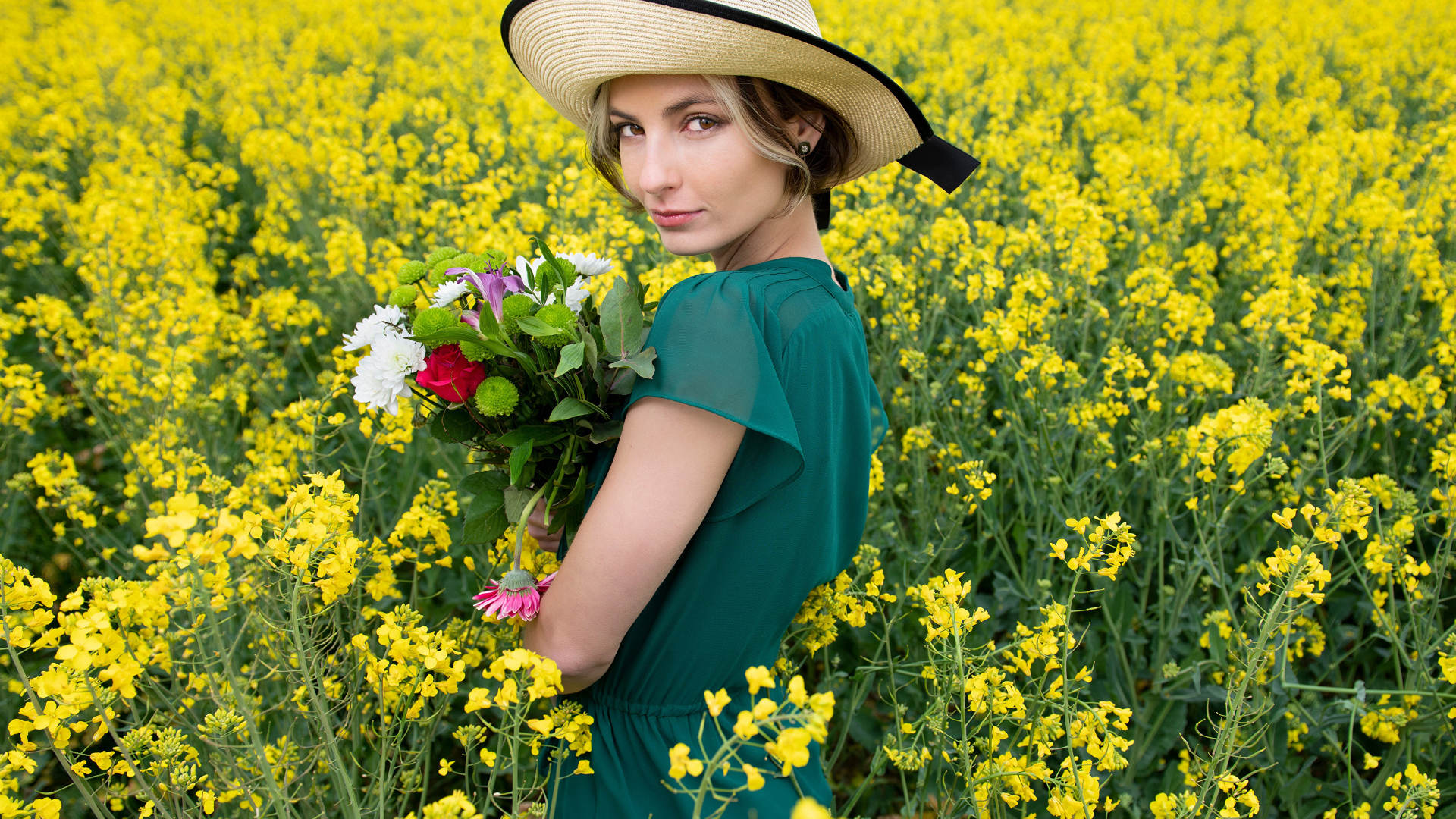 Красивая девушка в шляпе на поле с желтыми цветами летом