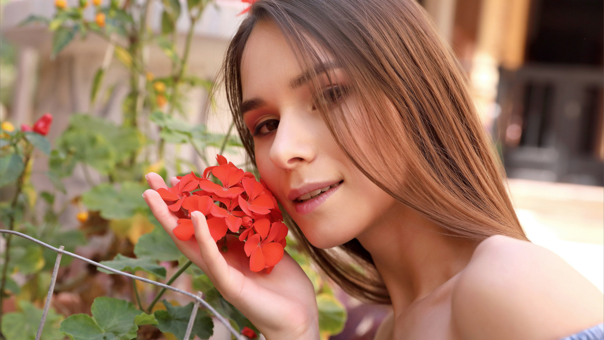 Красивая девушка с красным цветком герани 