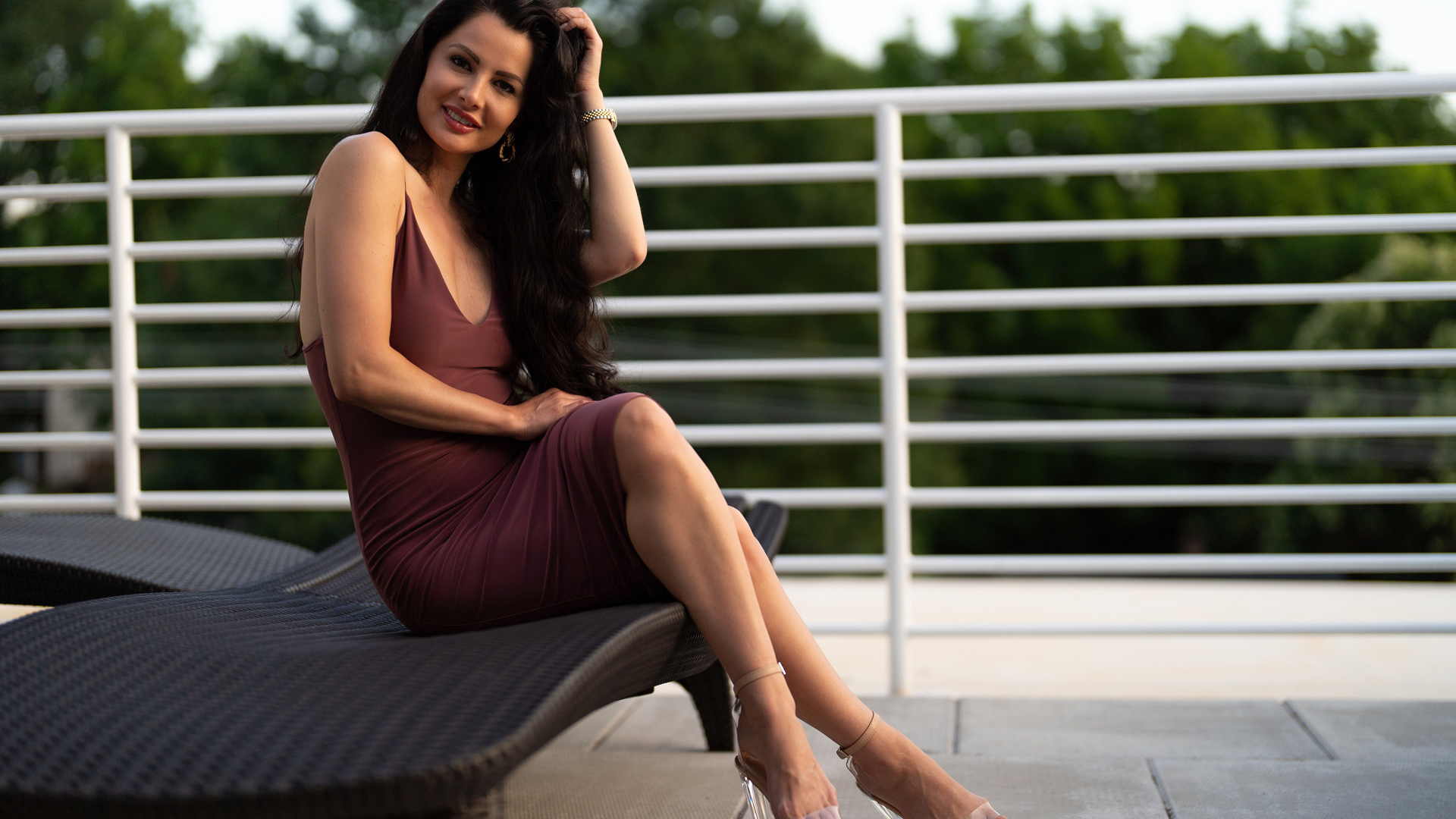 Красивая стильная брюнетка в платье сидит на диване